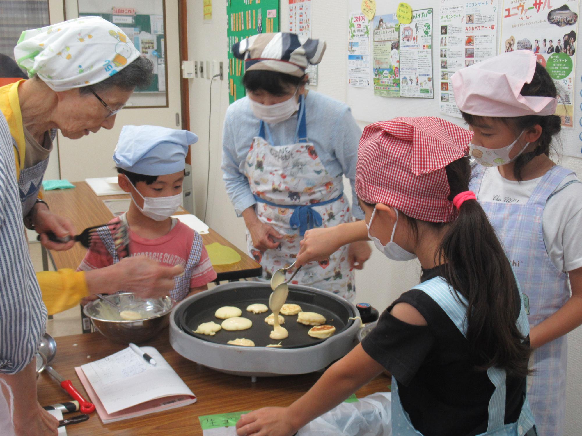 子ども達がホットプレートでパンケーキを焼いている写真