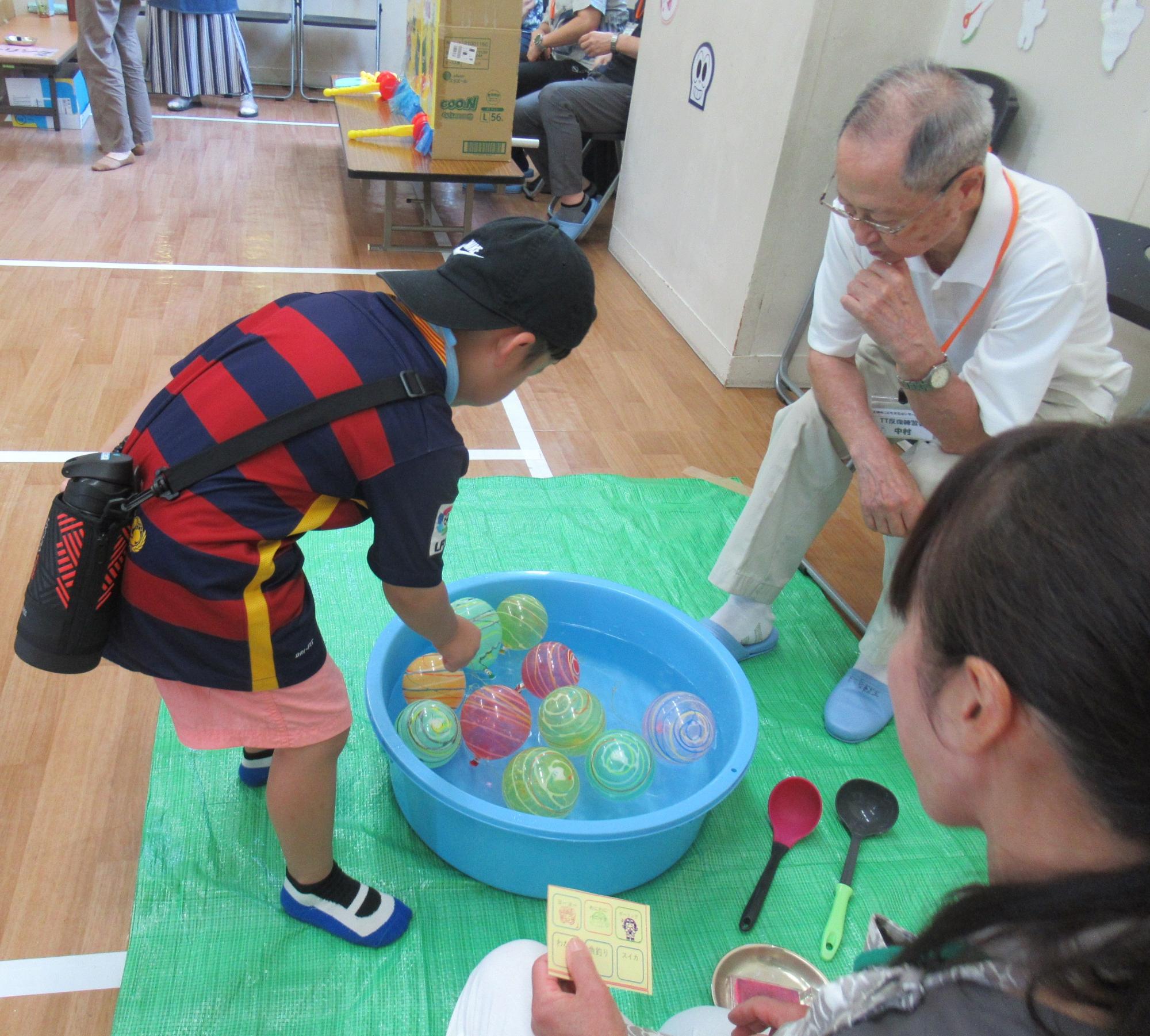 子どもがヨーヨー釣りゲームをしている写真