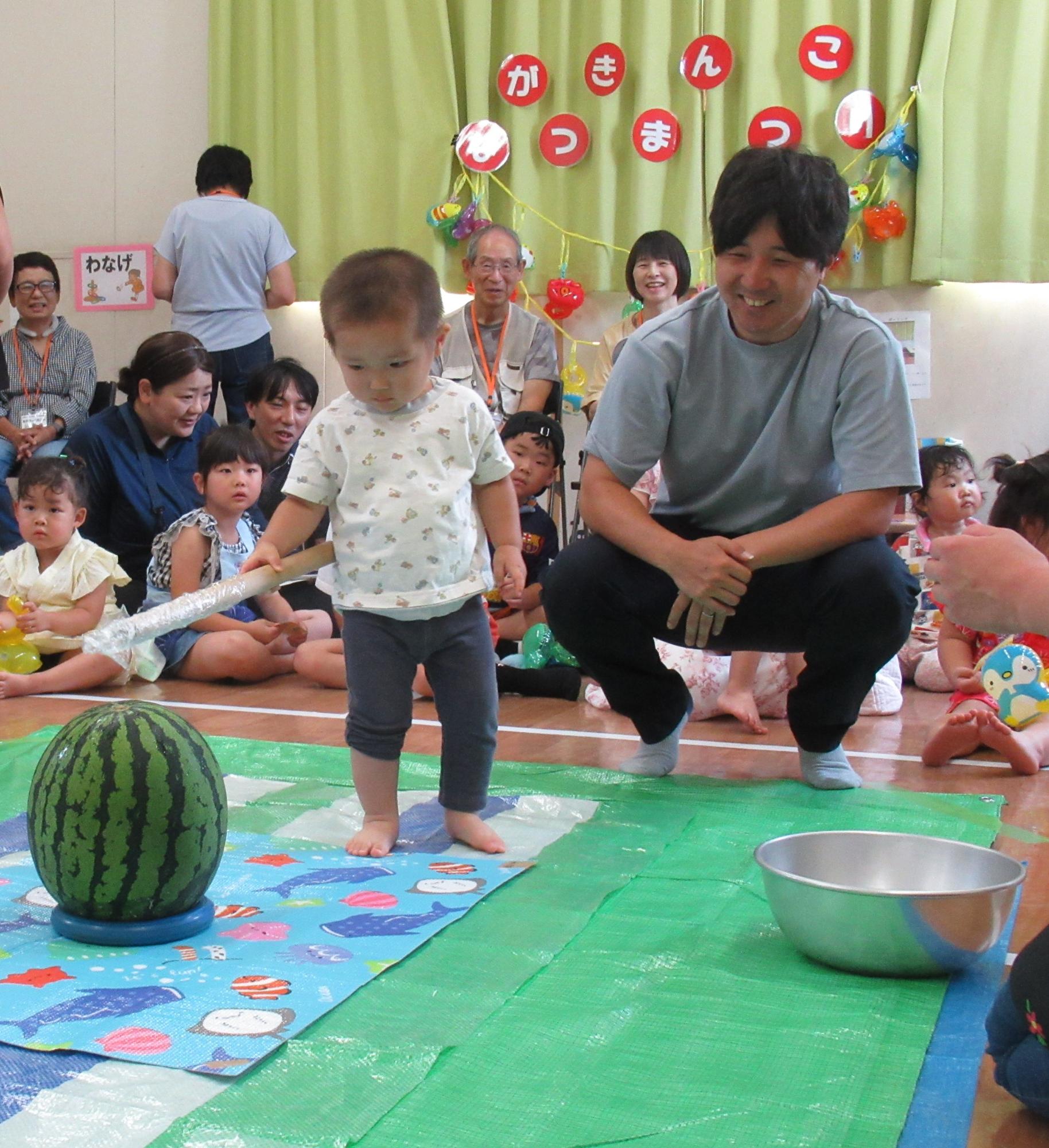 幼児がスイカ割りを楽しんでいる写真