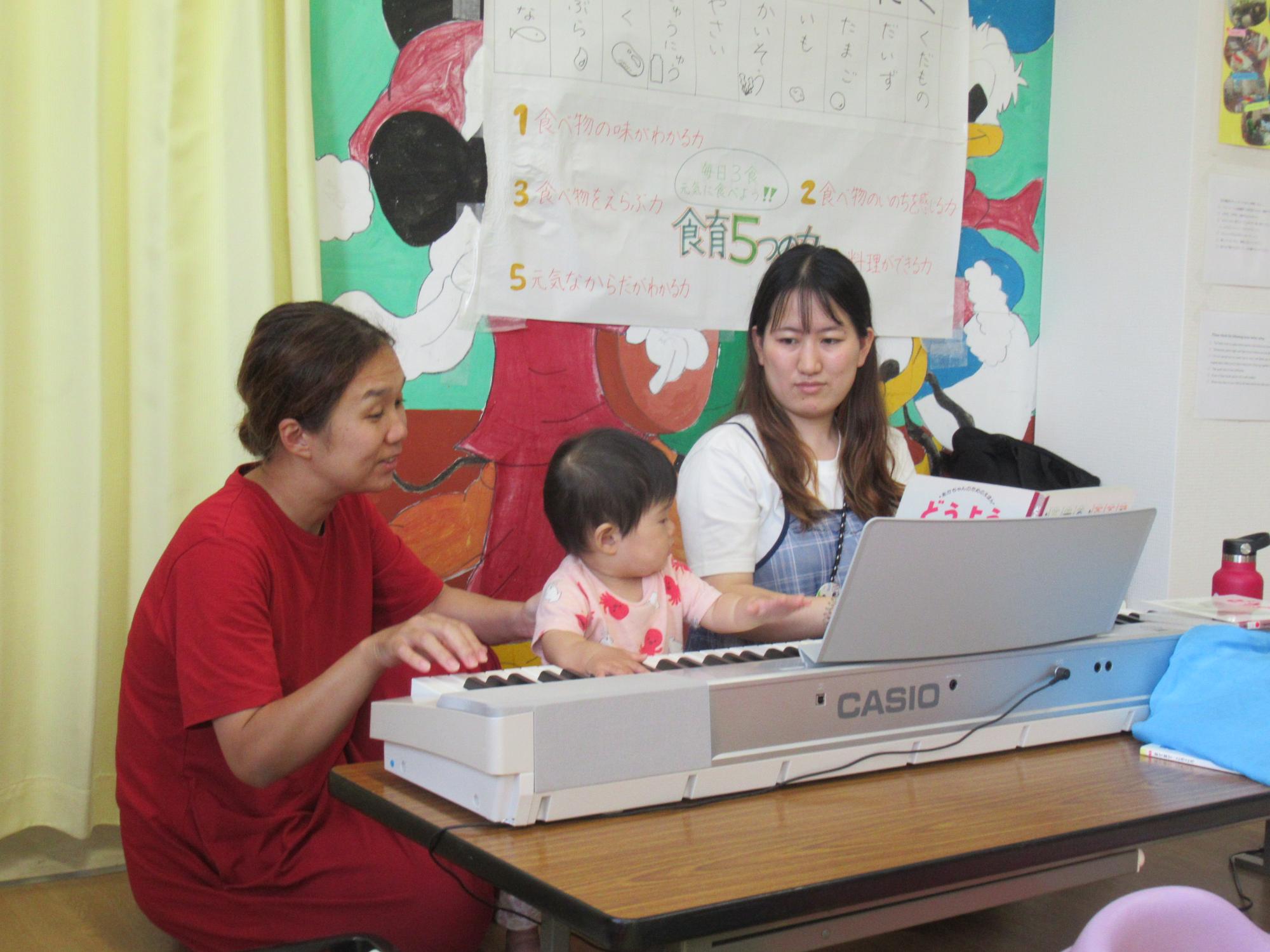 講師と幼児親子が電子ピアノを弾いている写真