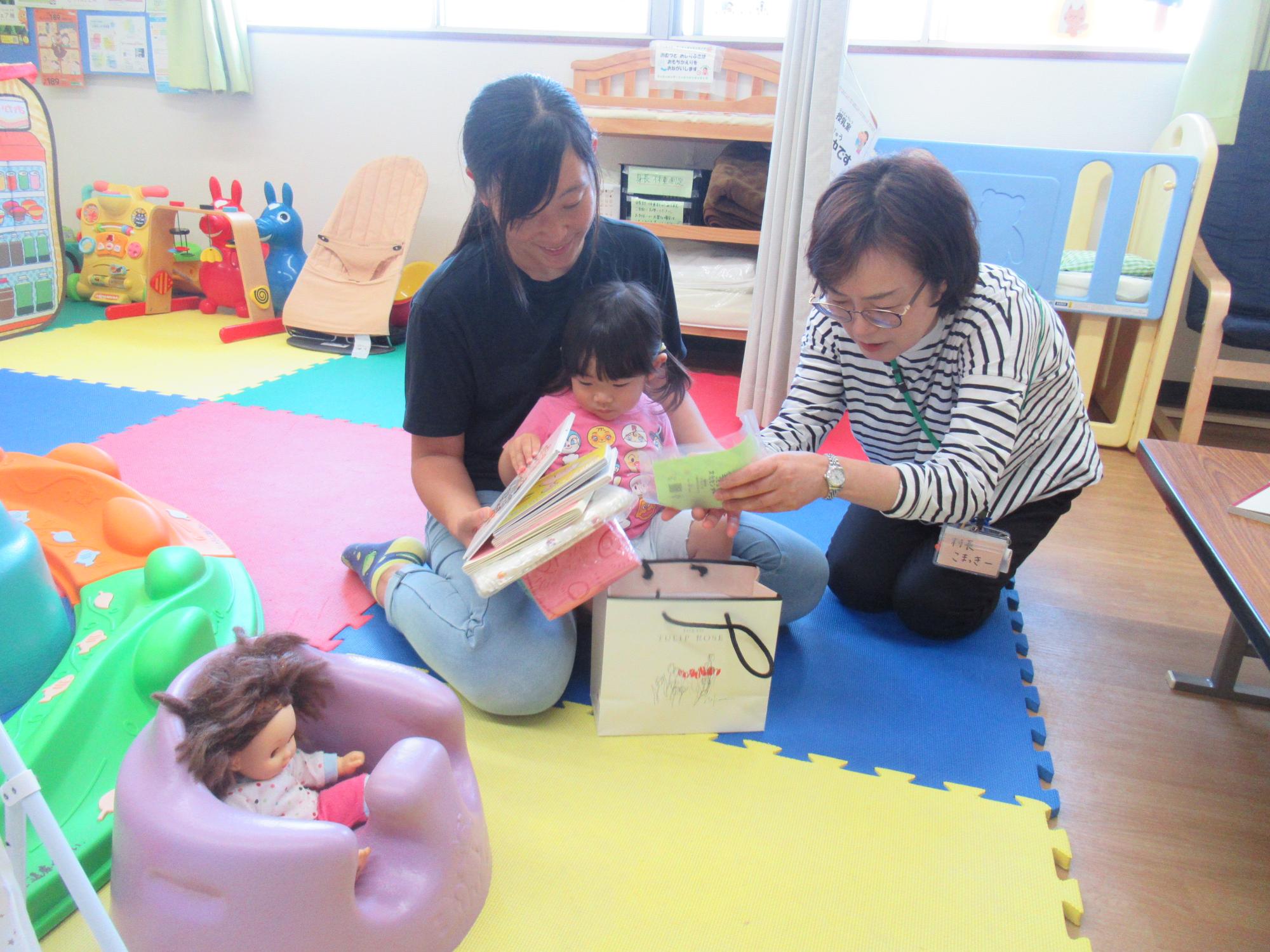 幼児親子の職員が誕生日プレゼントを見ている写真