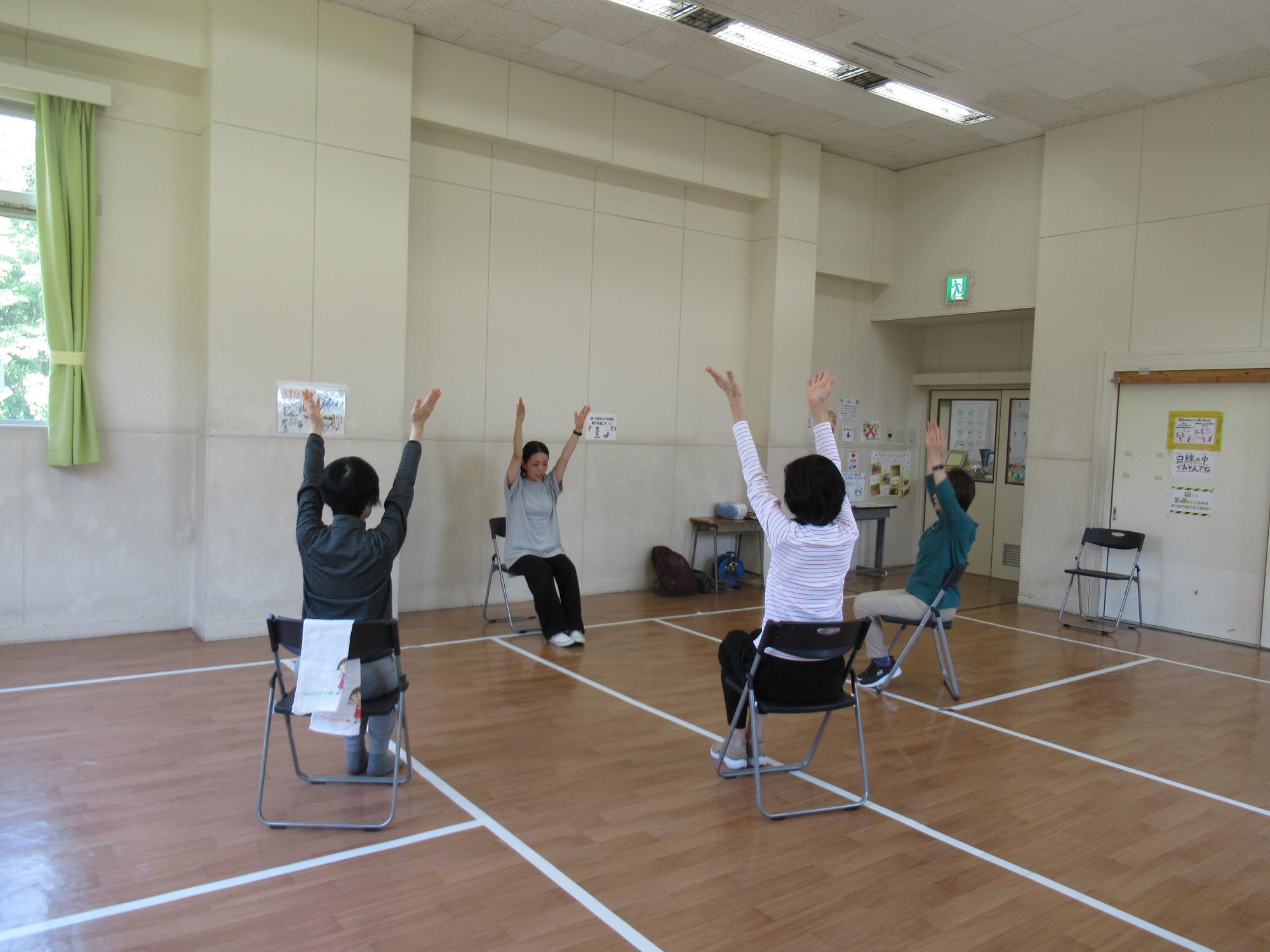 成人が椅子に座って手をあげて体操をしている写真