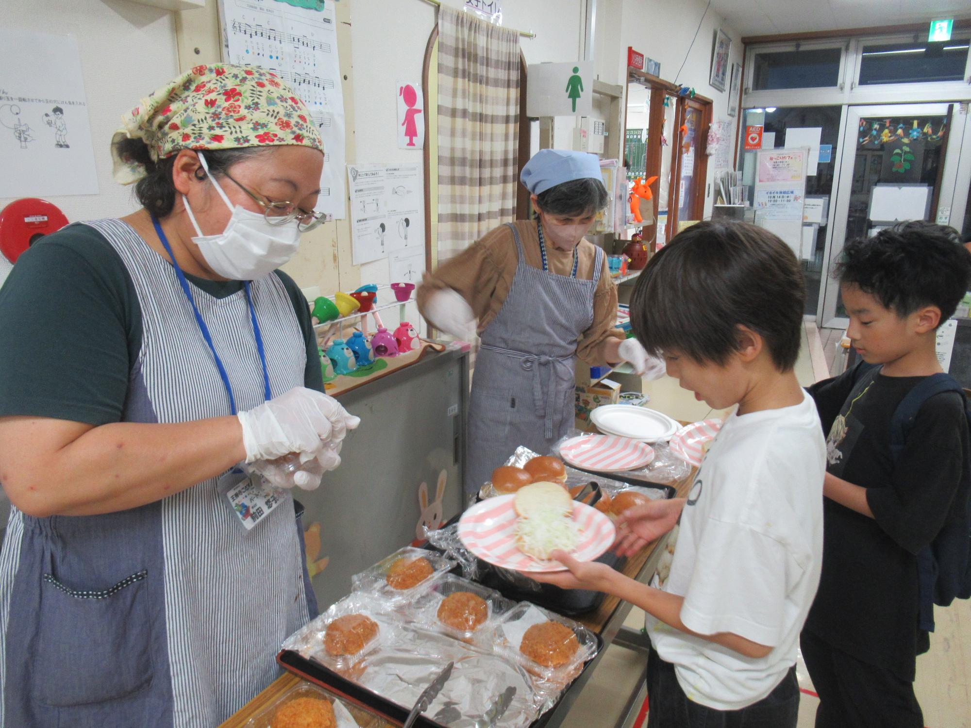 メンチカツバーガーを自分で作っている小学生の写真