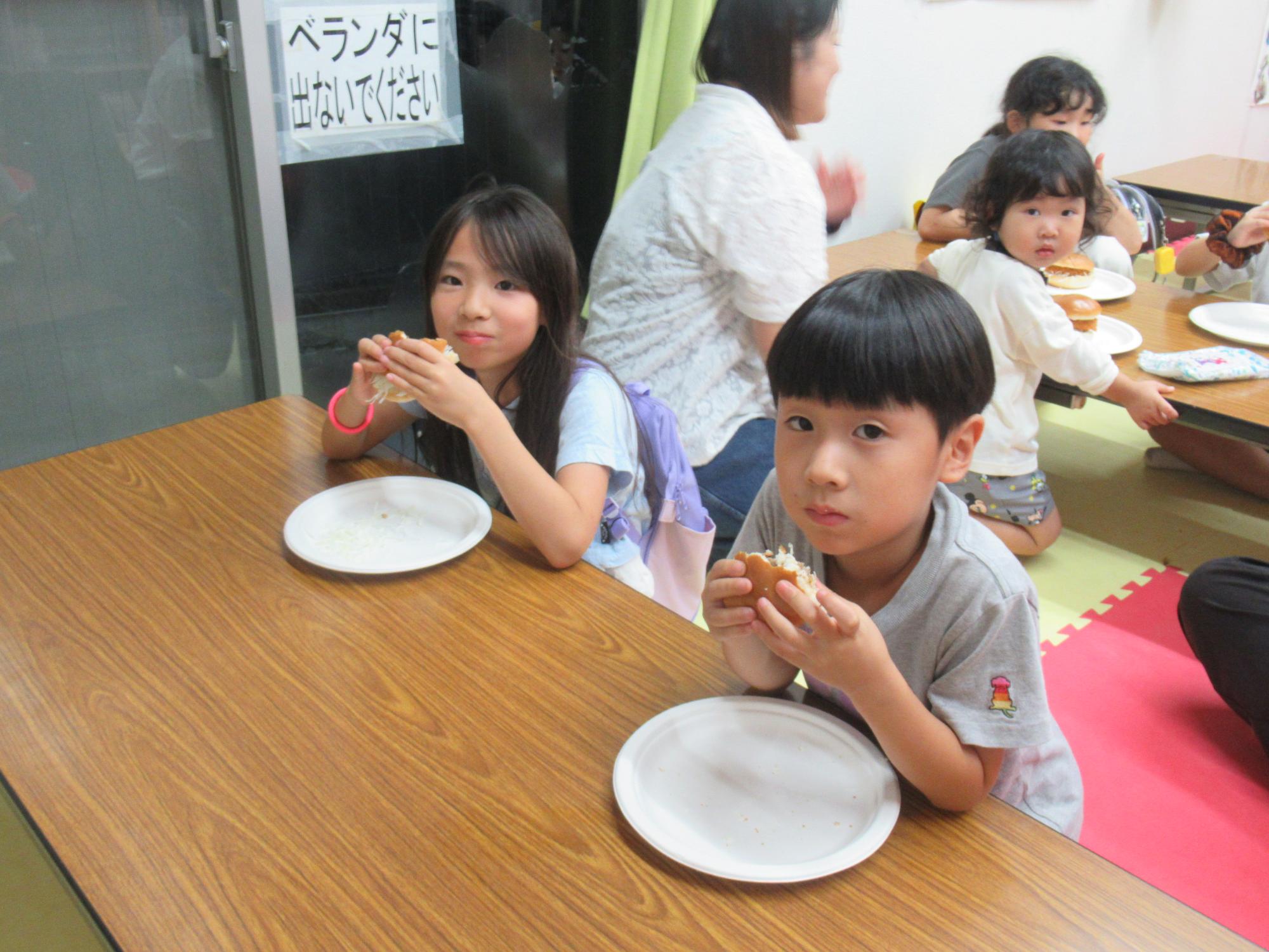 メンチカツバーガーを食べる子どもの写真