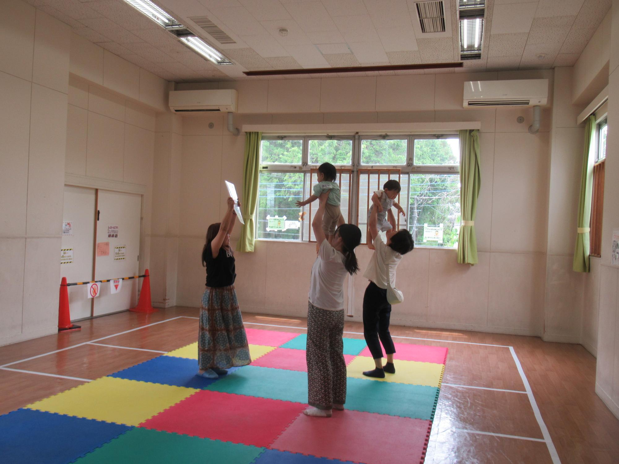 講師とリトミックをする親子の写真