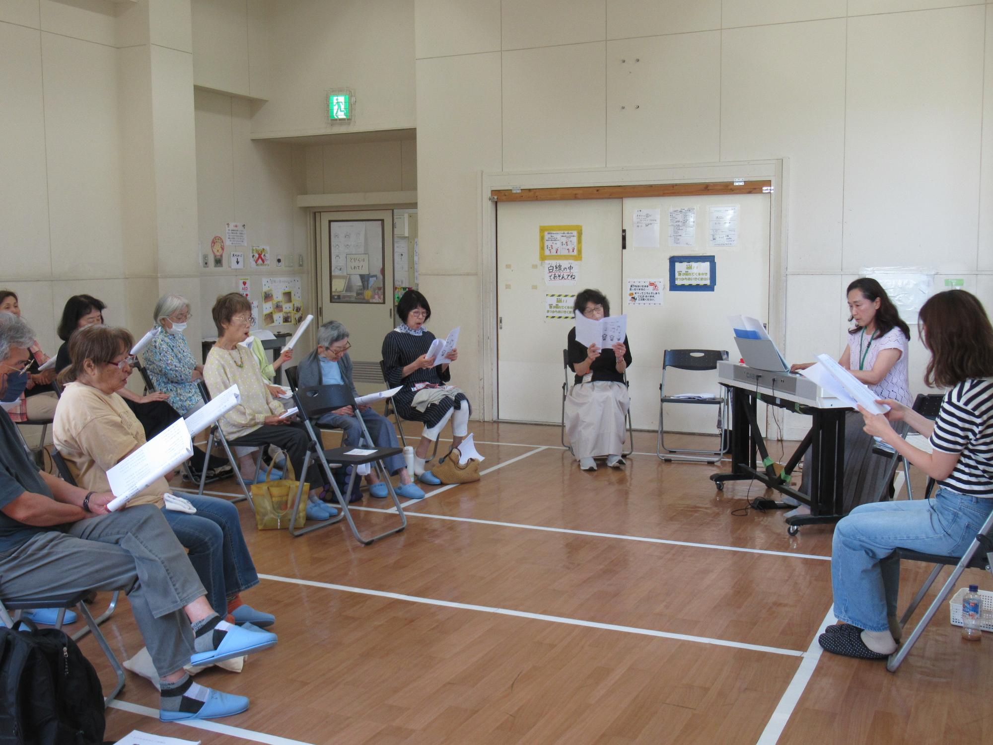 参加者が講師のピアノの演奏に合わせて歌詞カードを見ながら歌を歌っている写真2