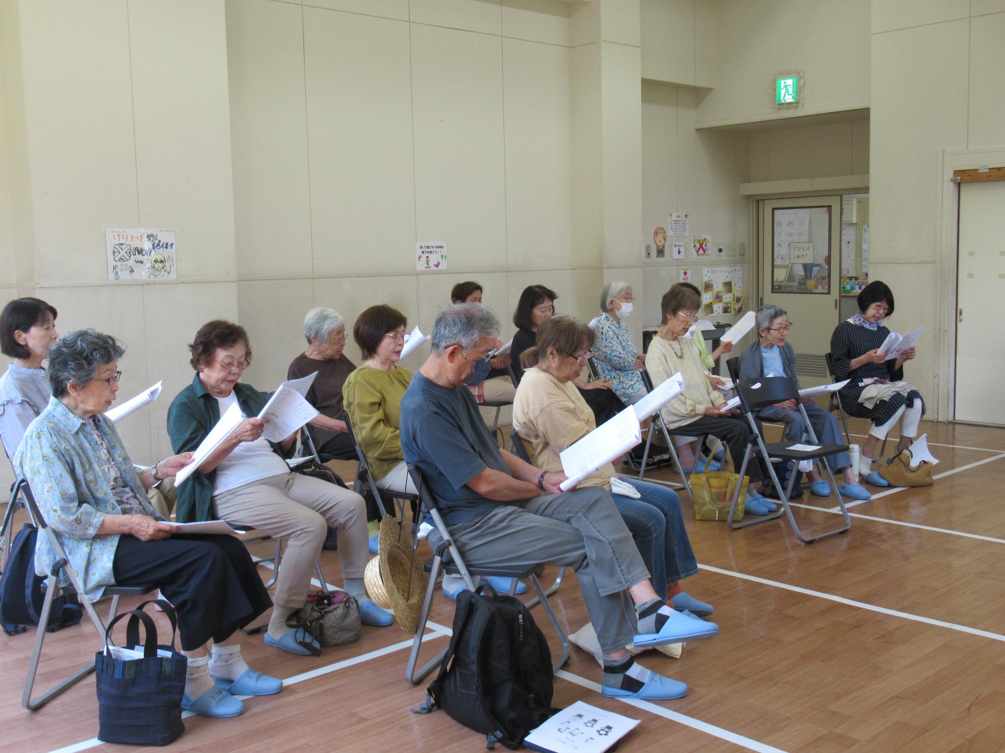 参加者が歌詞カードを見ながら歌を歌っている写真