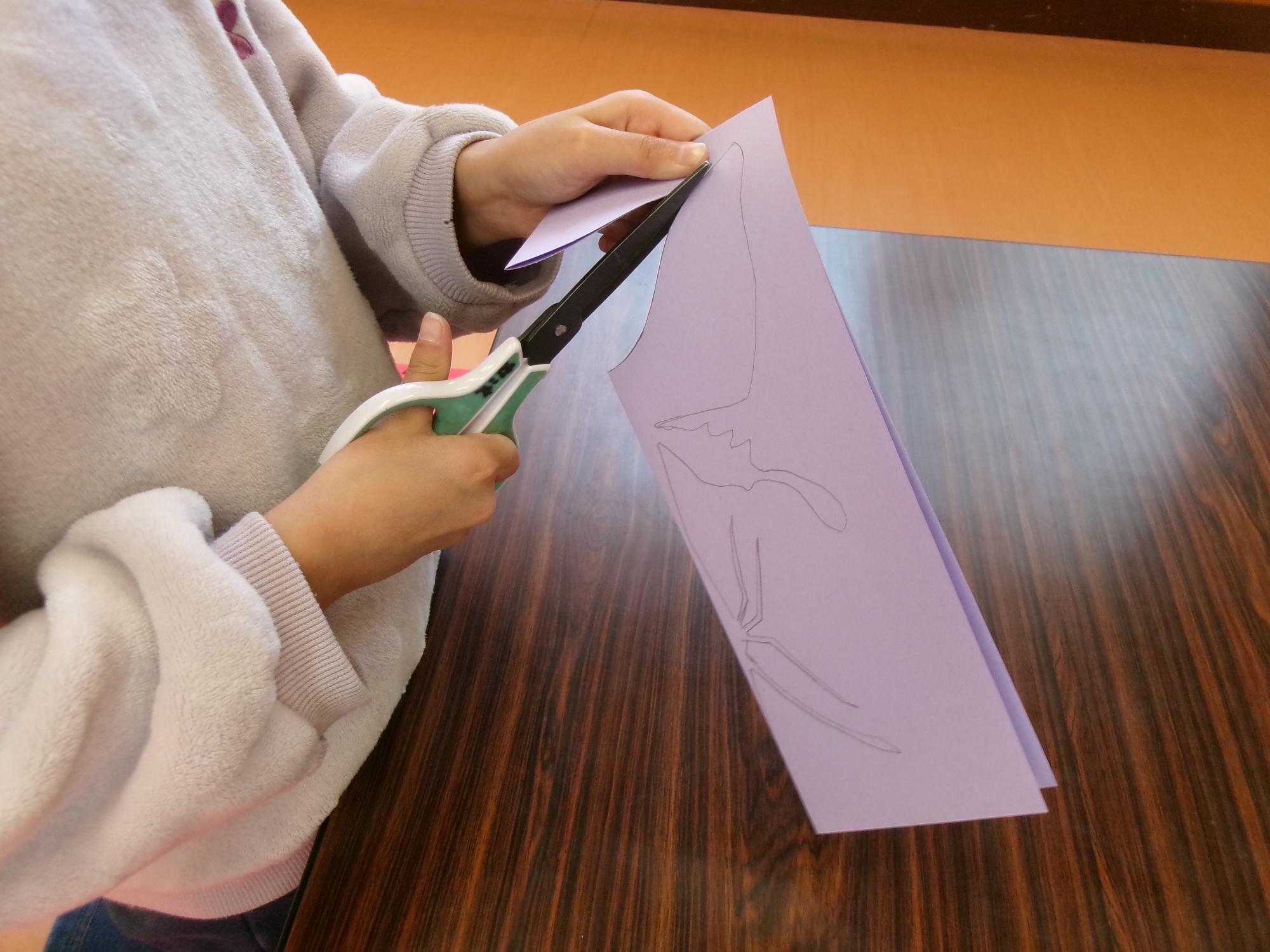 厚紙に描かれた線にそって切っている様子