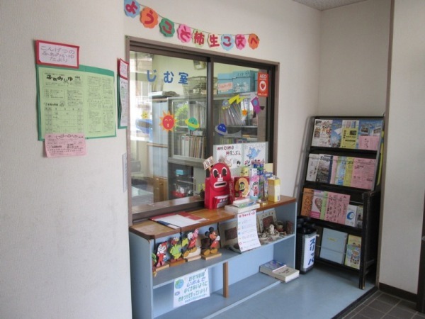受付窓の上に「ようこそ柿生こ文へ」と書かれた紙が貼られており、窓口に帳簿の置かれた受付の写真