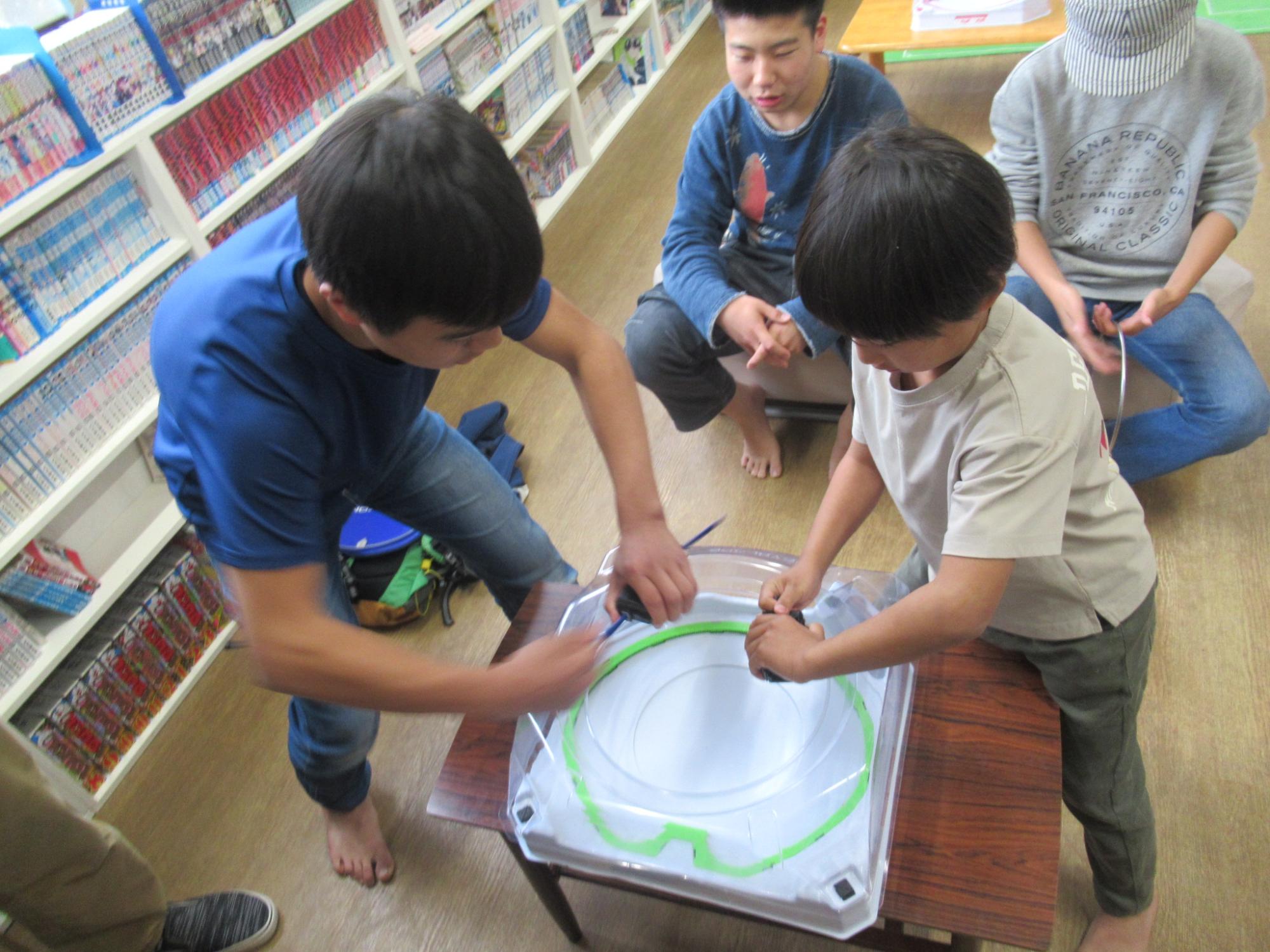 ベイブレードをしている小学生と中学生の写真