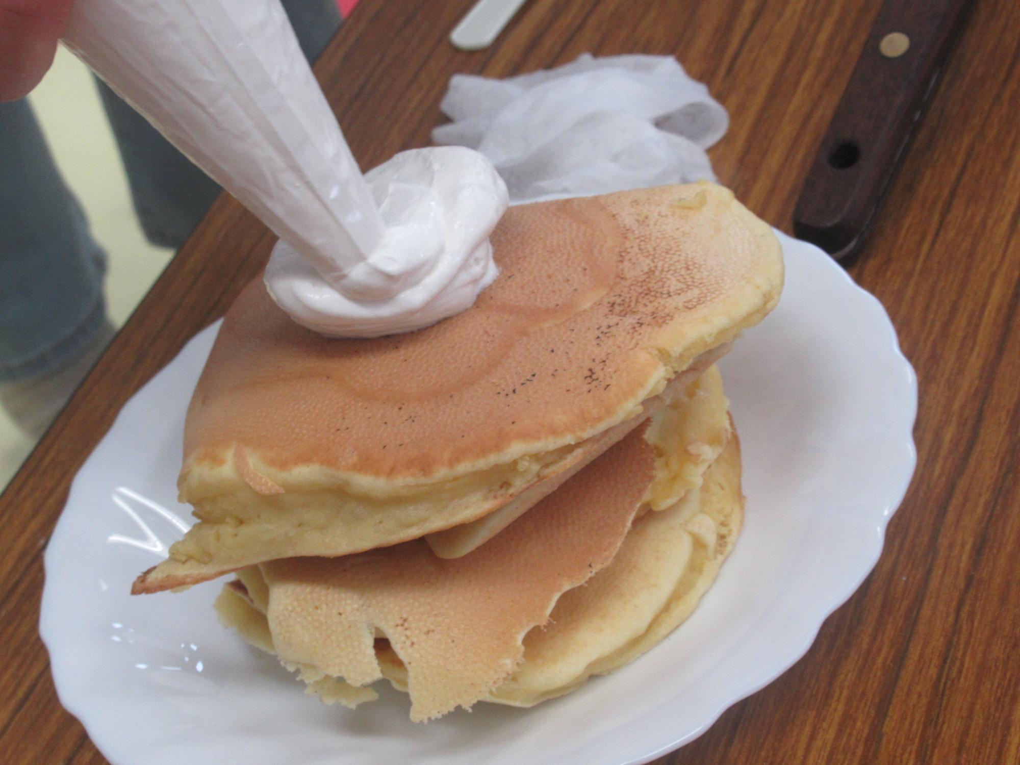 生クリームをホットケーキにかけている写真