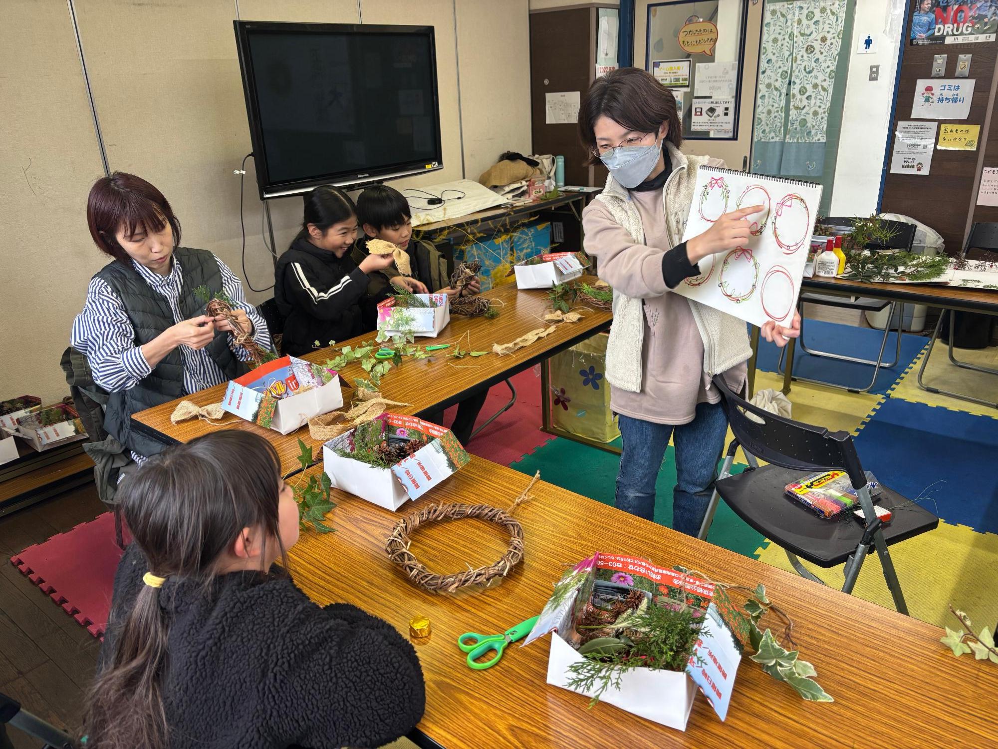 リース作りを子どもに教えている大人の写真