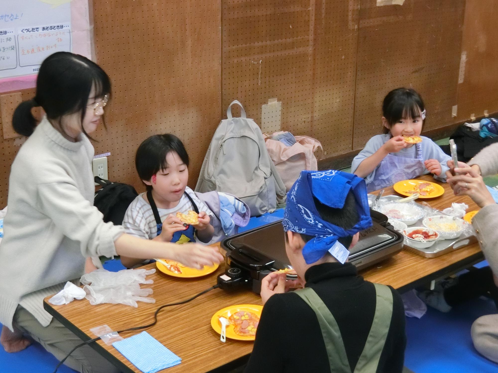 完成したぎょうざの皮ピザを食べている様子
