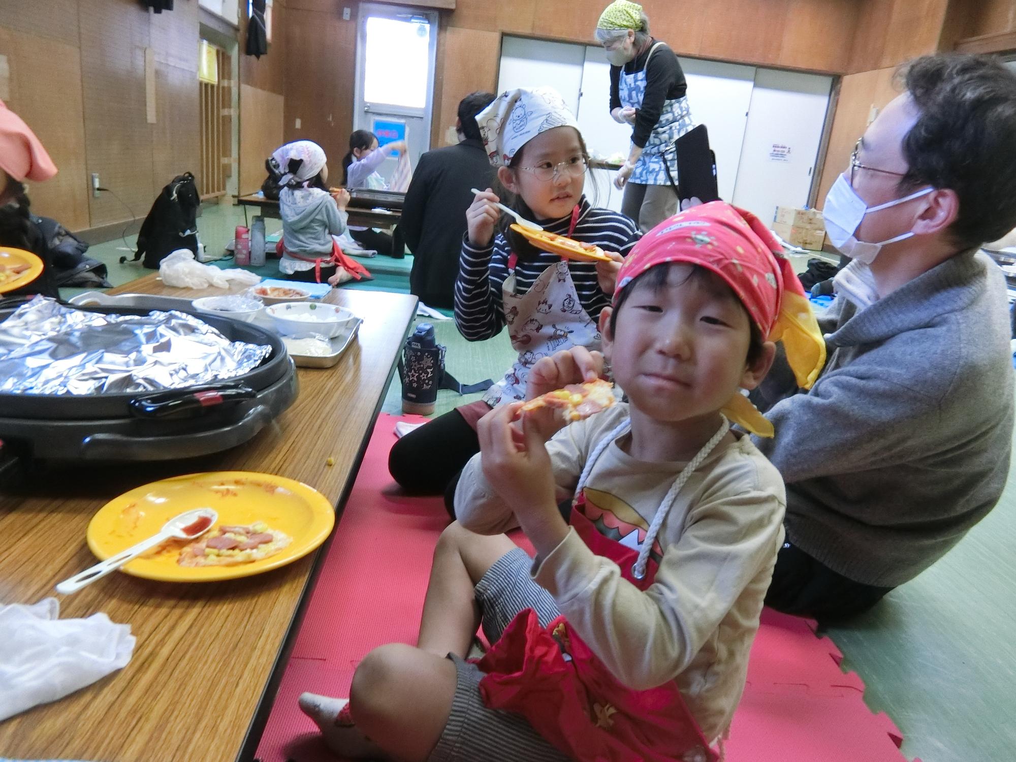 完成したぎょうざの皮ピザを食べている様子