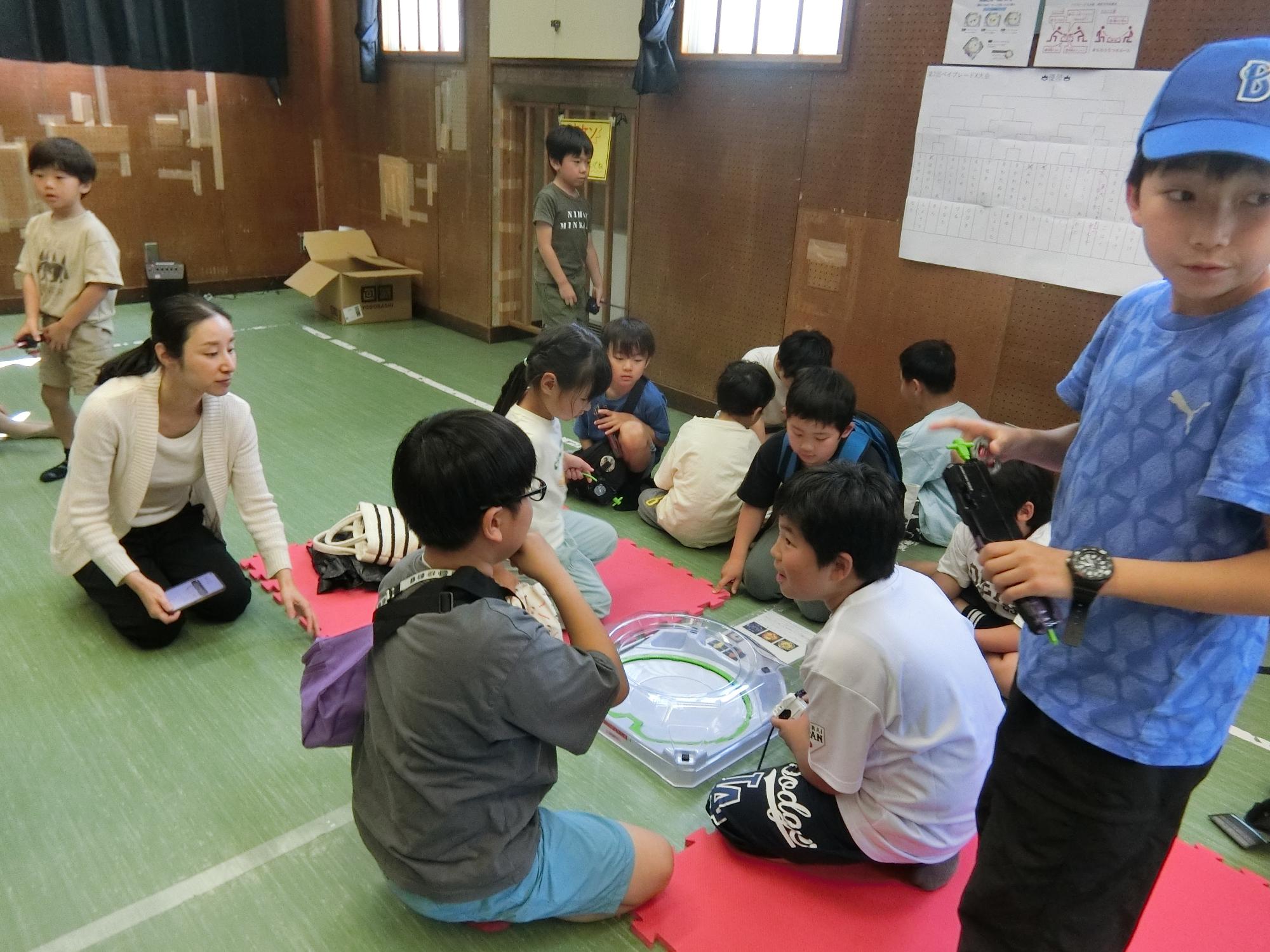 ベイブレードの対戦を周りの子が見守っている様子