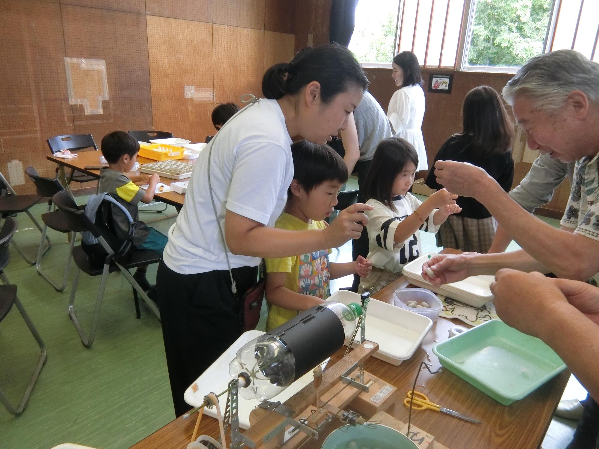 参加者が糸繰り体験をしている様子