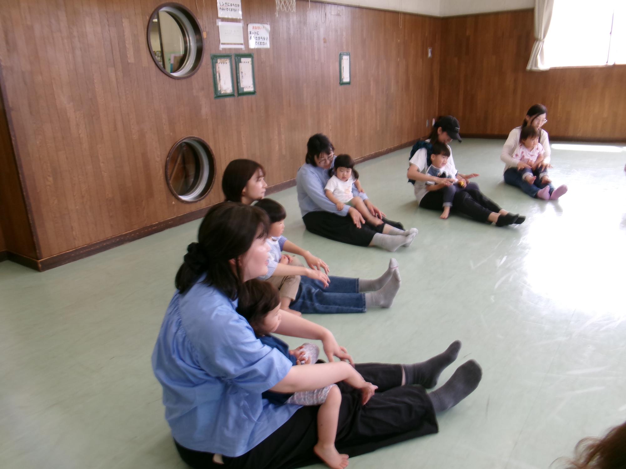 お母さんの膝にすわり英語のリズム遊びをしている写真