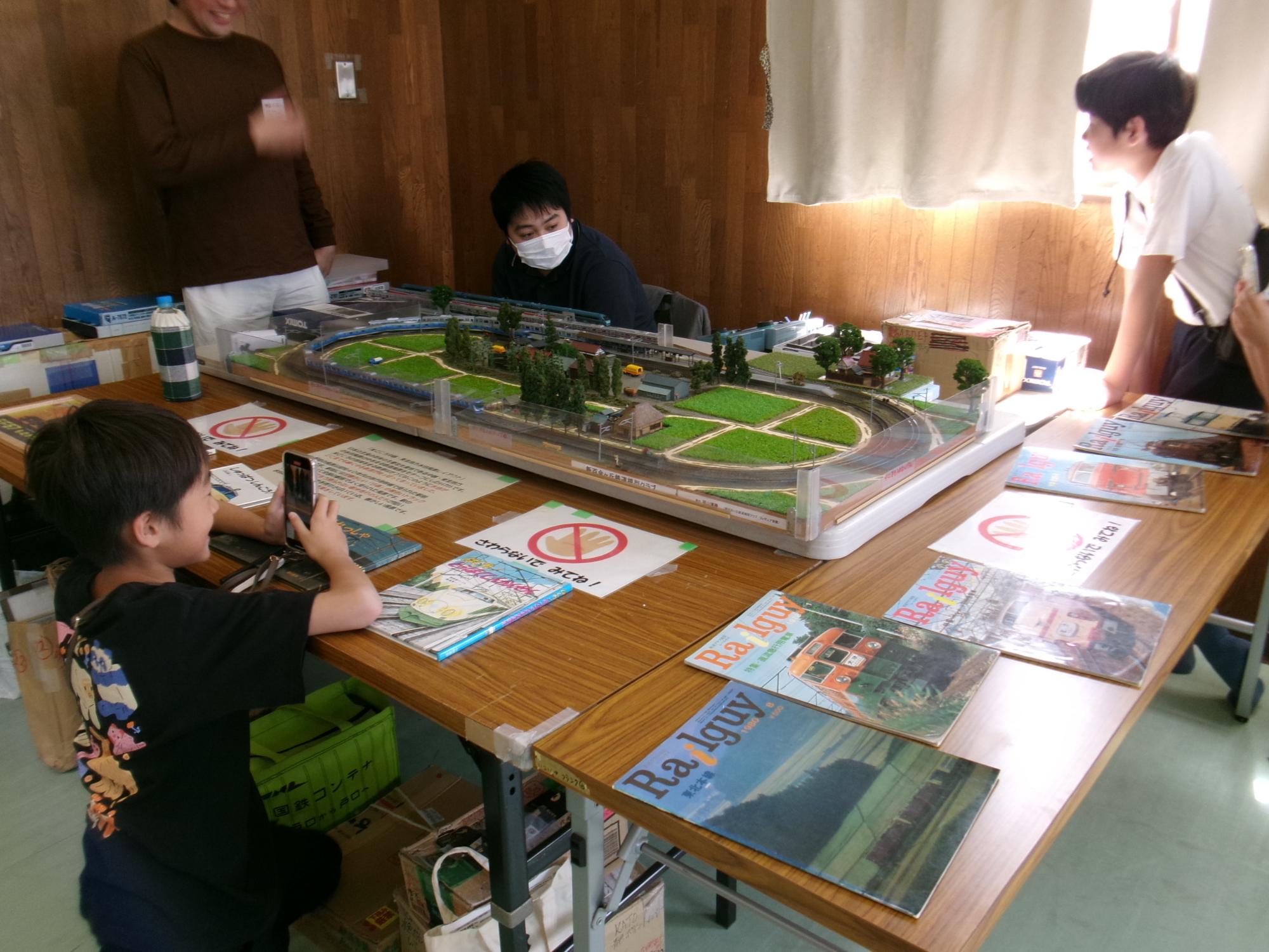 参加した中学生児童が鉄道模型の写真を撮っている様子の写真
