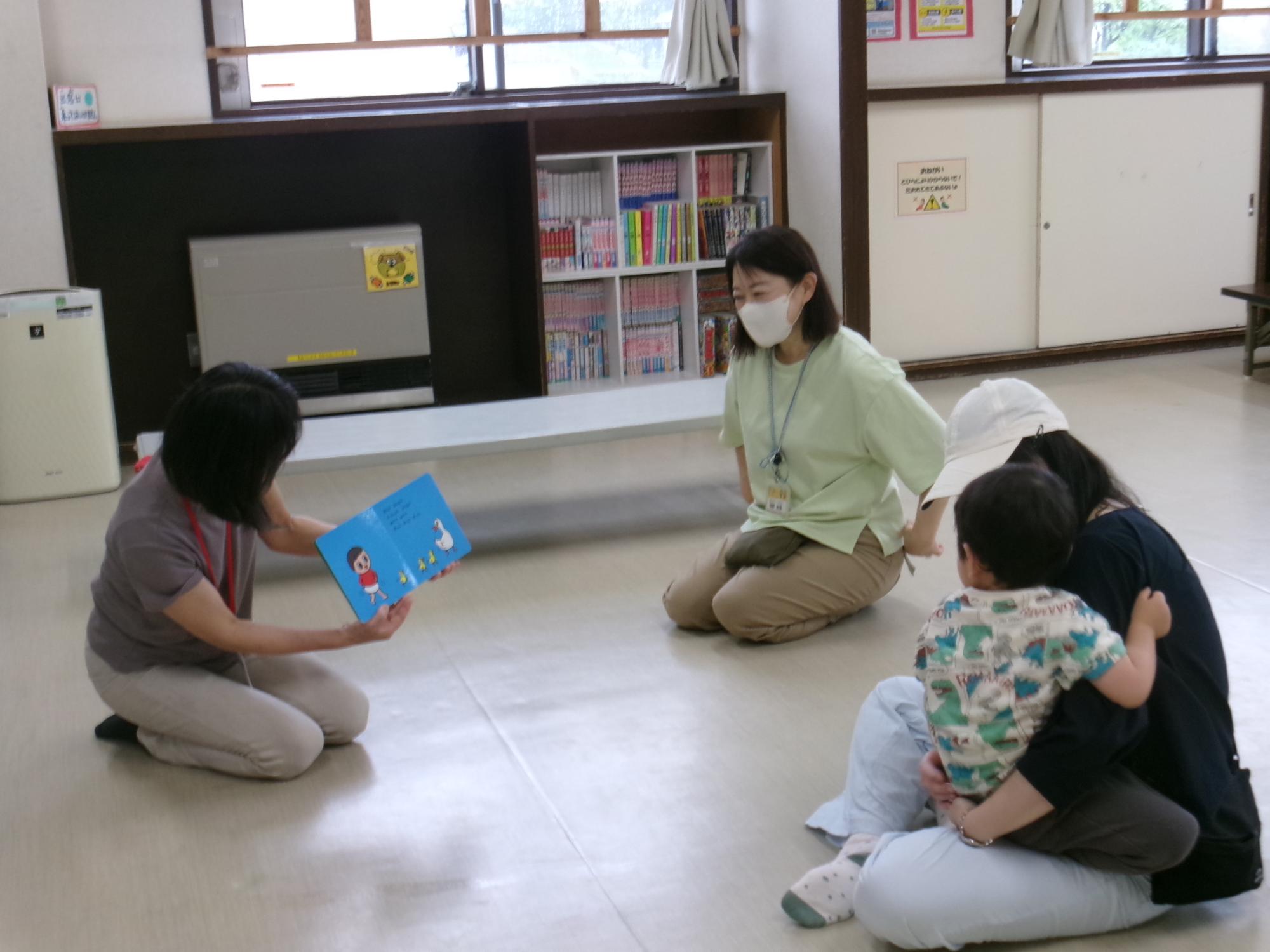 ボランティアの方々による読み聞かせを聞いている乳幼児親子の様子の写真