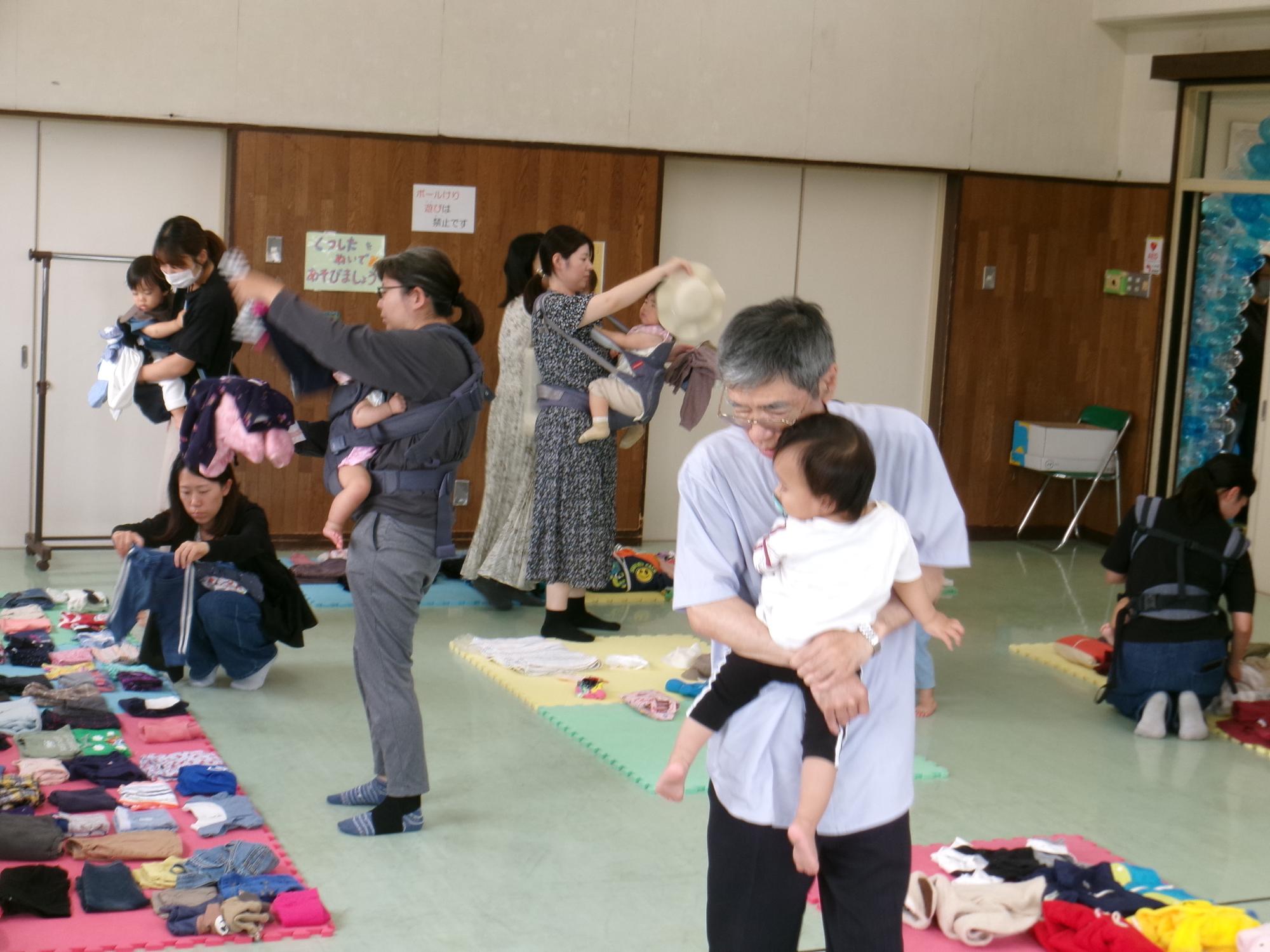 ちびっこマルシェに参加してこども服を吟味して選ぶ乳幼児親子の様子の写真