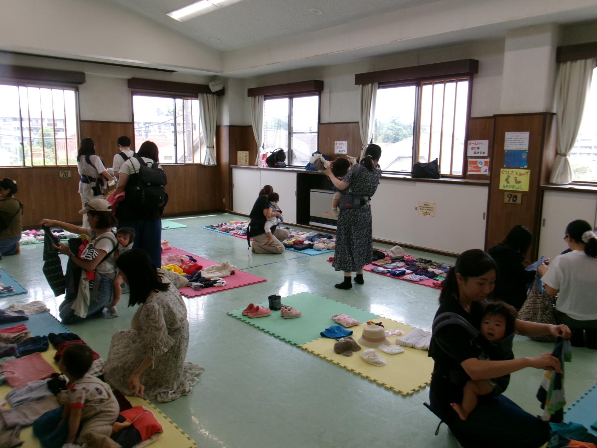 ちびっこマルシェに参加してこども服を吟味して選ぶ乳幼児親子の様子の写真
