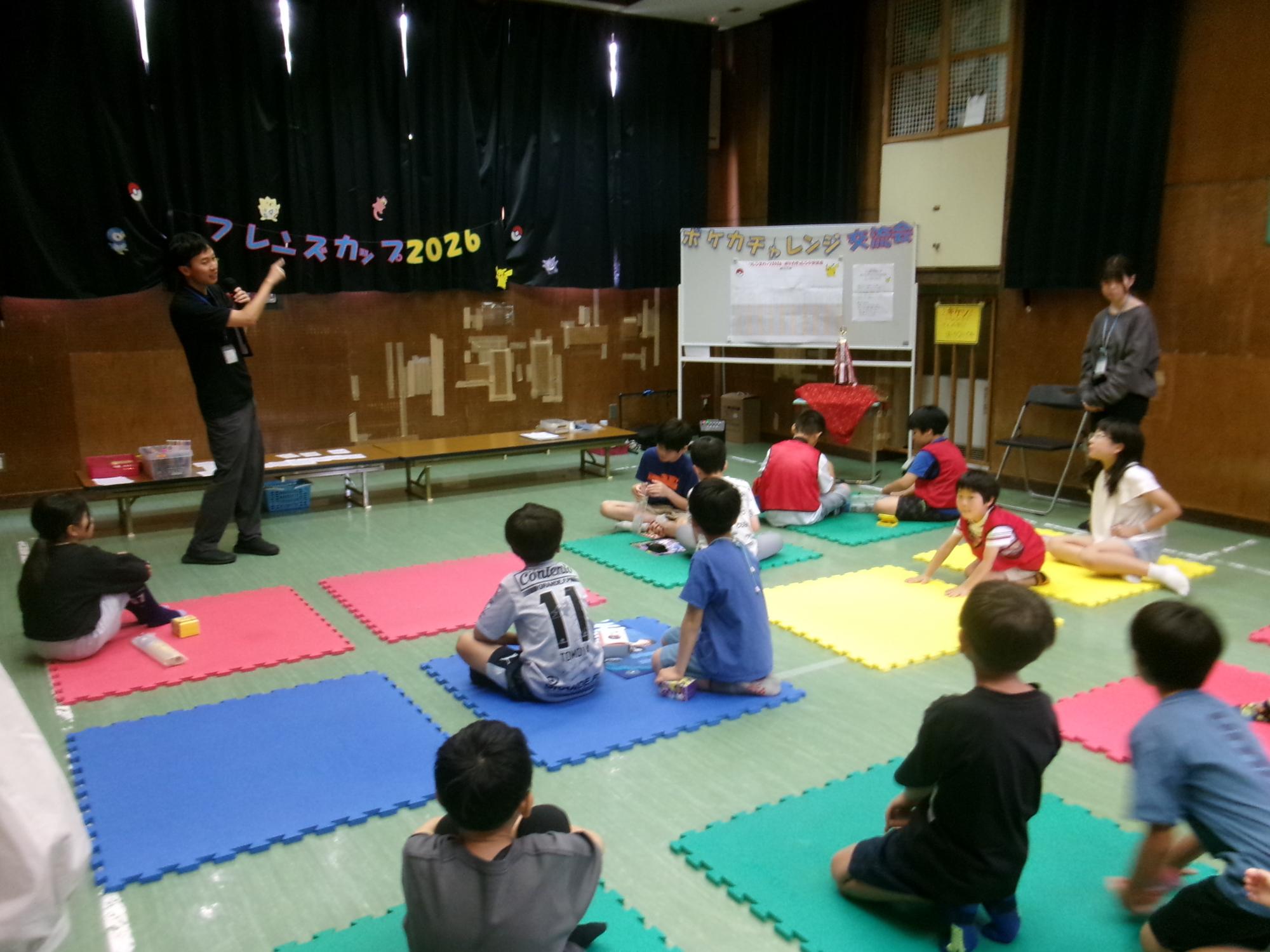 ポケカチャレンジ交流会について職員の説明を聞く参加児童の様子の写真