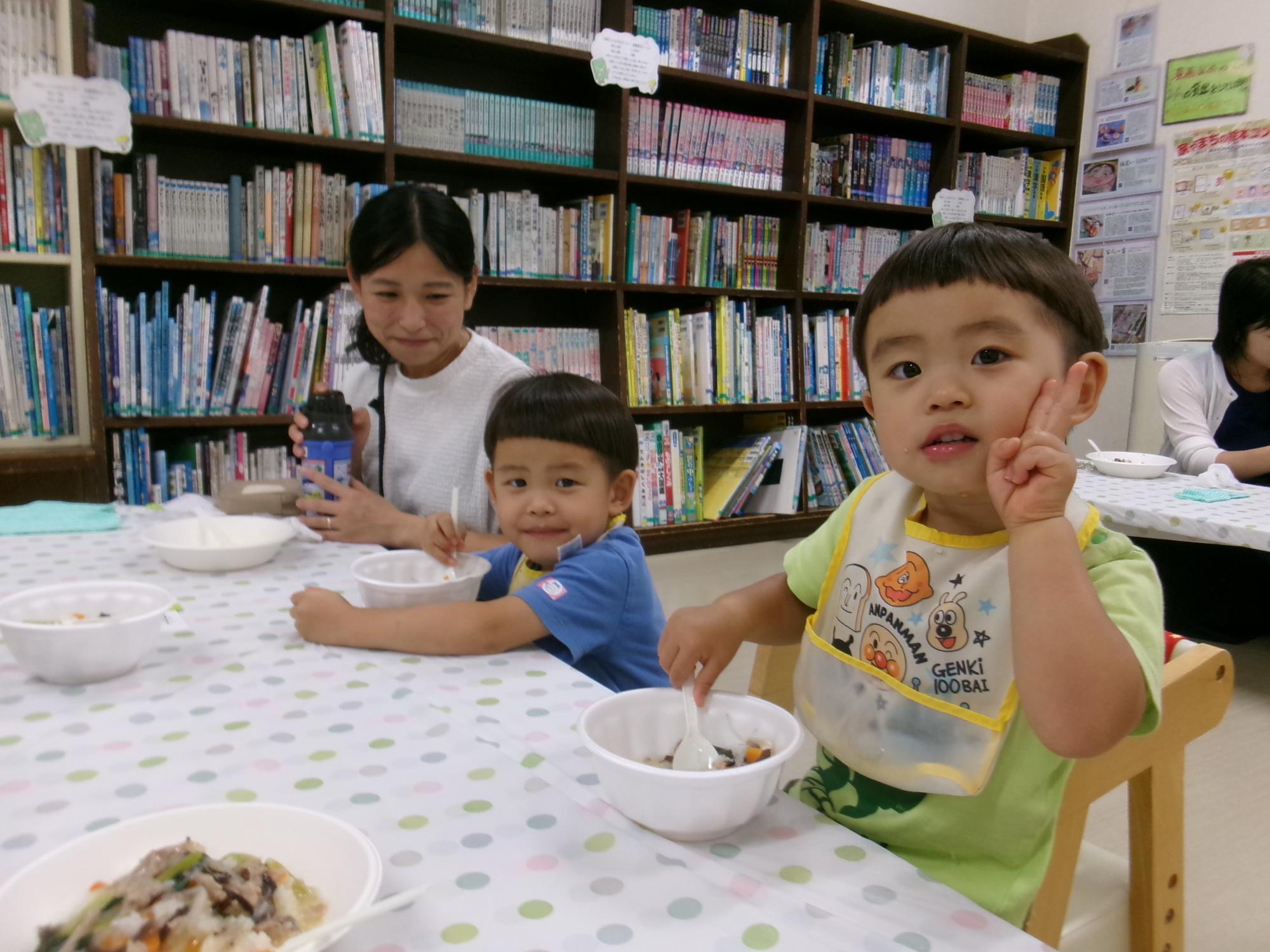 おいしそうに中華丼を食べる乳幼児親子の写真
