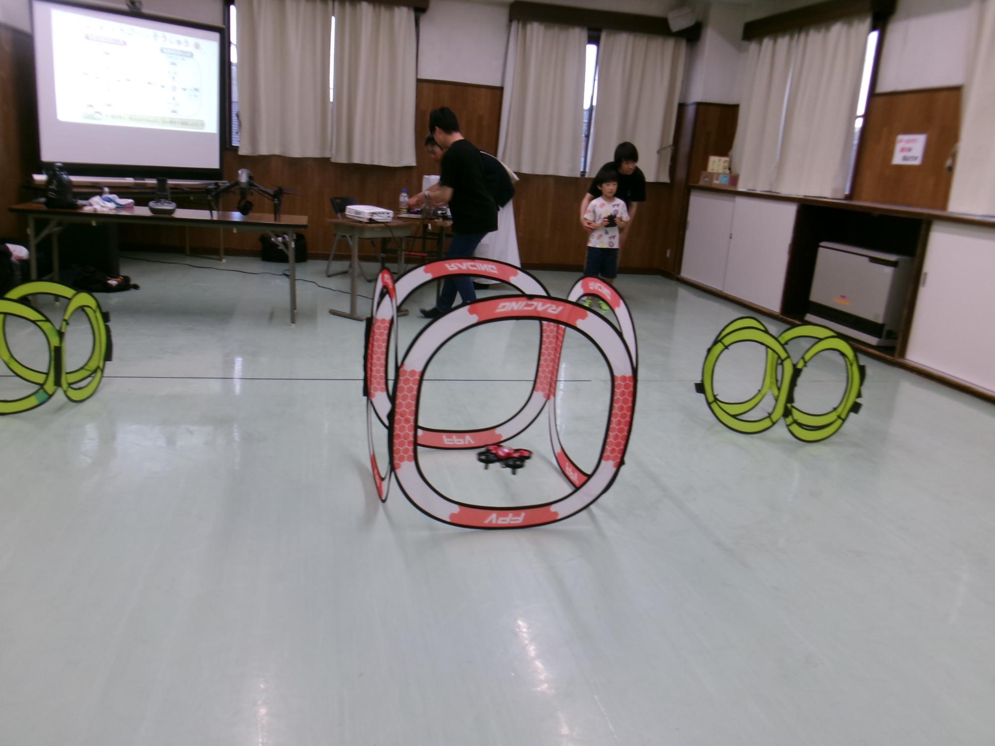 小型のドローンが輪の中をくぐる様子の写真