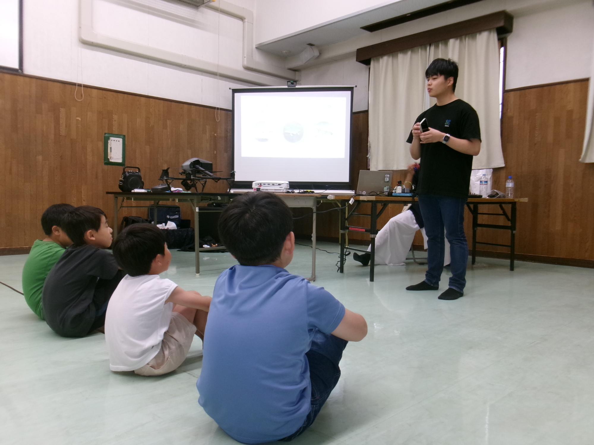 講師の説明を熱心に聞く小学生の参加者の様子の写真