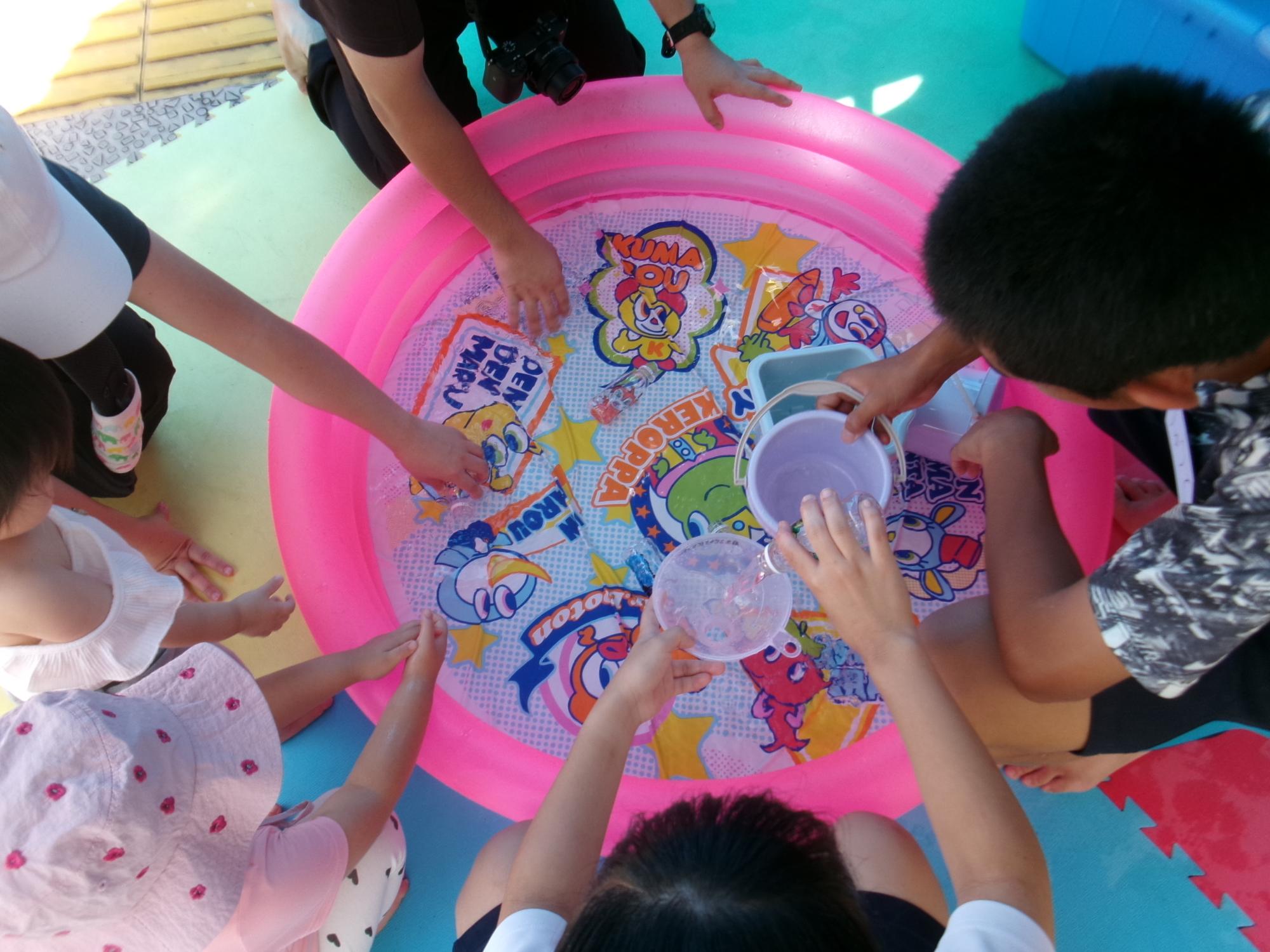 中学生が幼児と一緒に水遊びをしている様子の写真