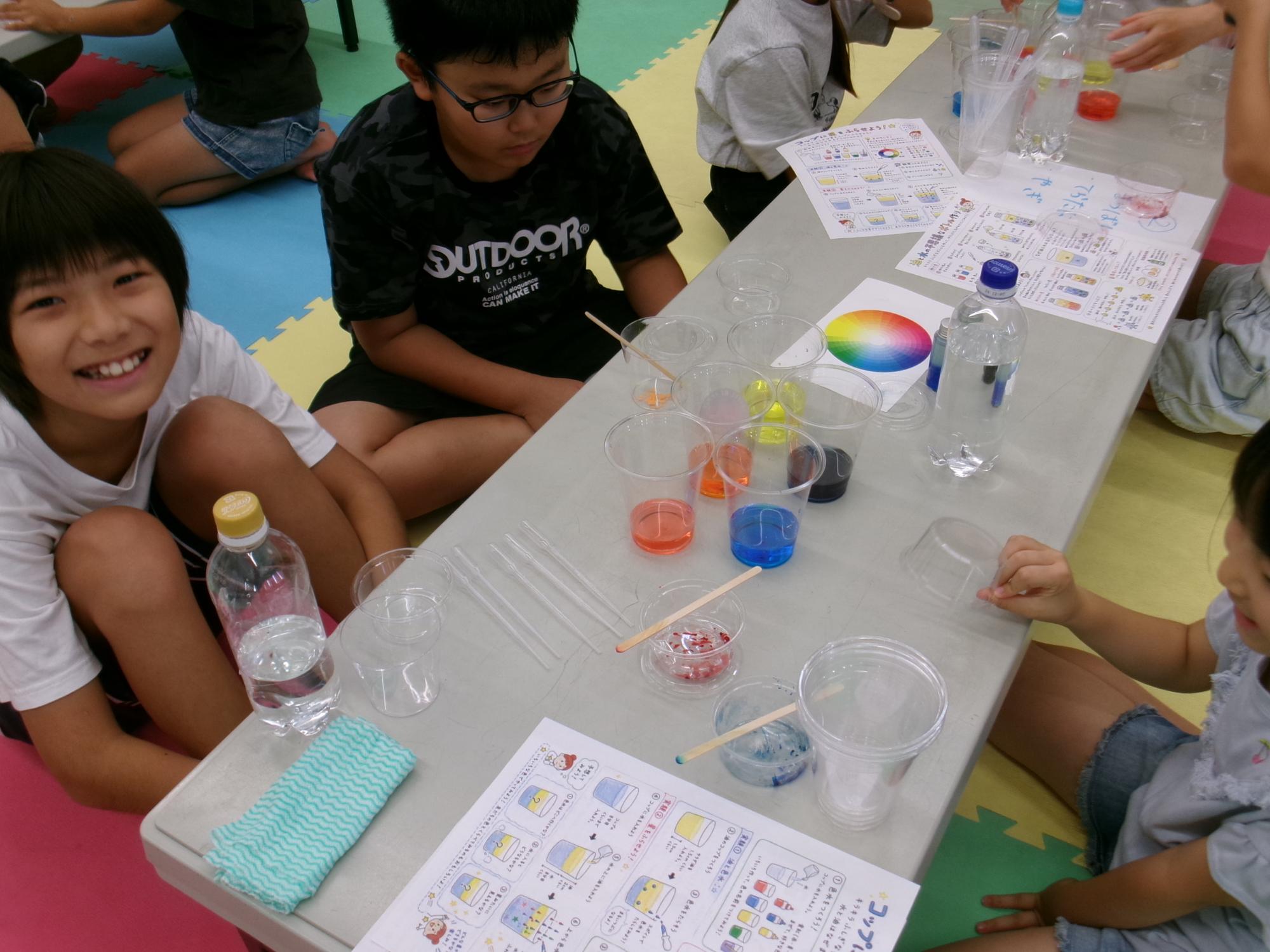 食紅を溶かした色水を作っている小学生児童の様子の写真