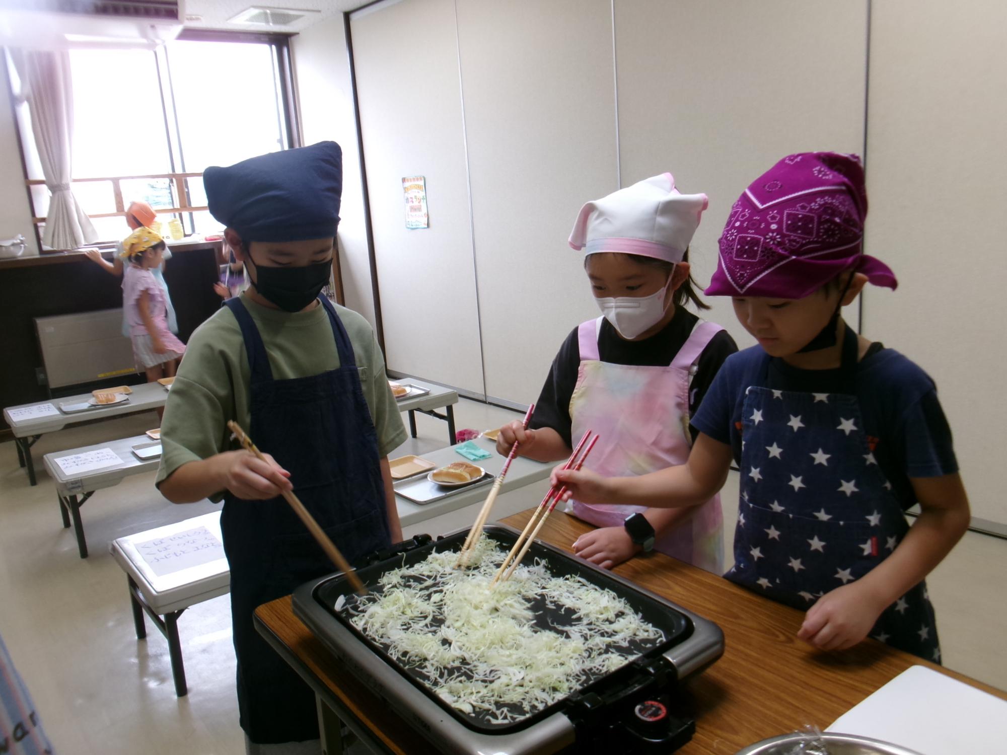 キャベツを炒めている小学生児童の様子の写真