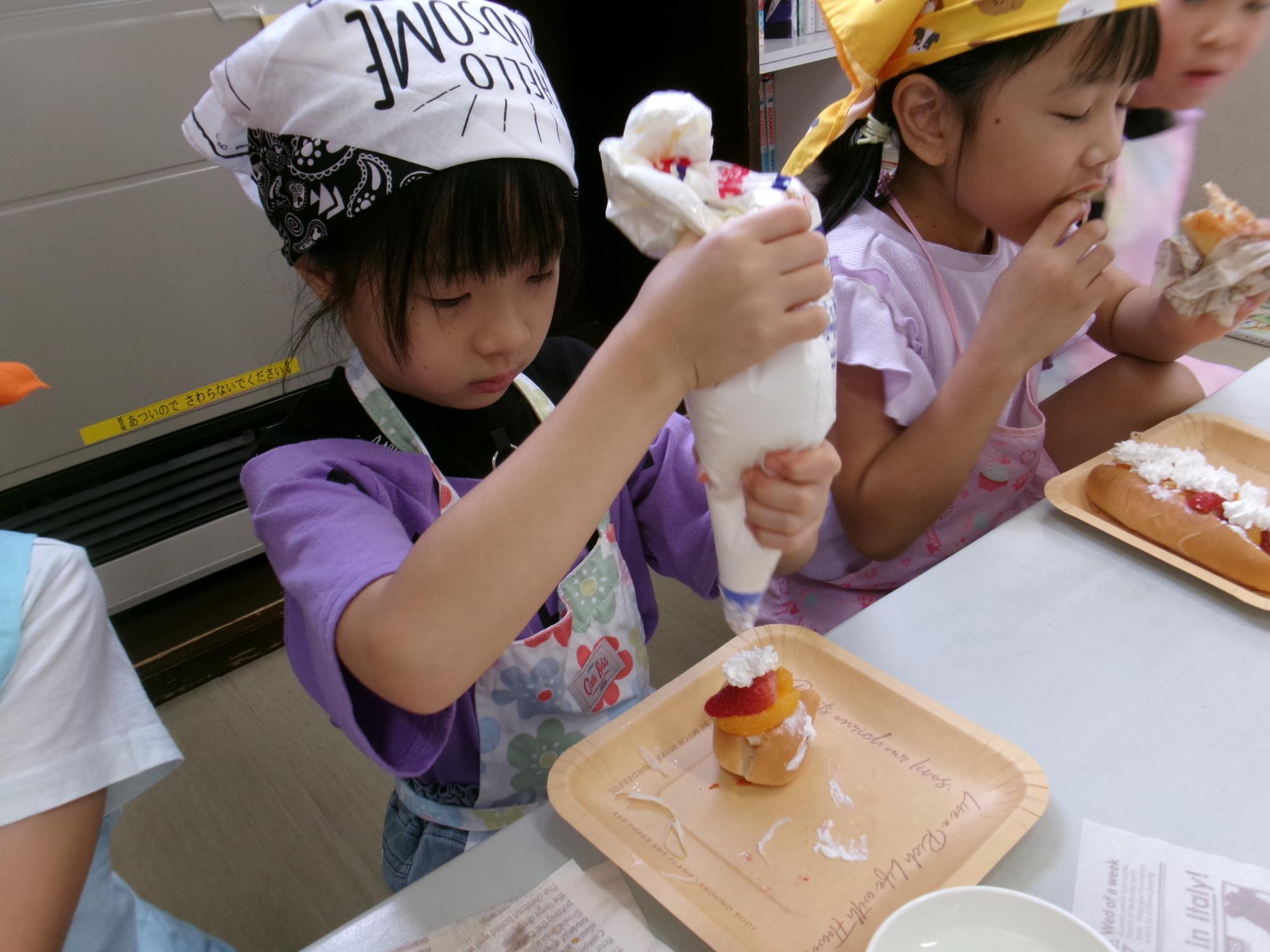 生クリームを絞る小学生児童の様子の写真
