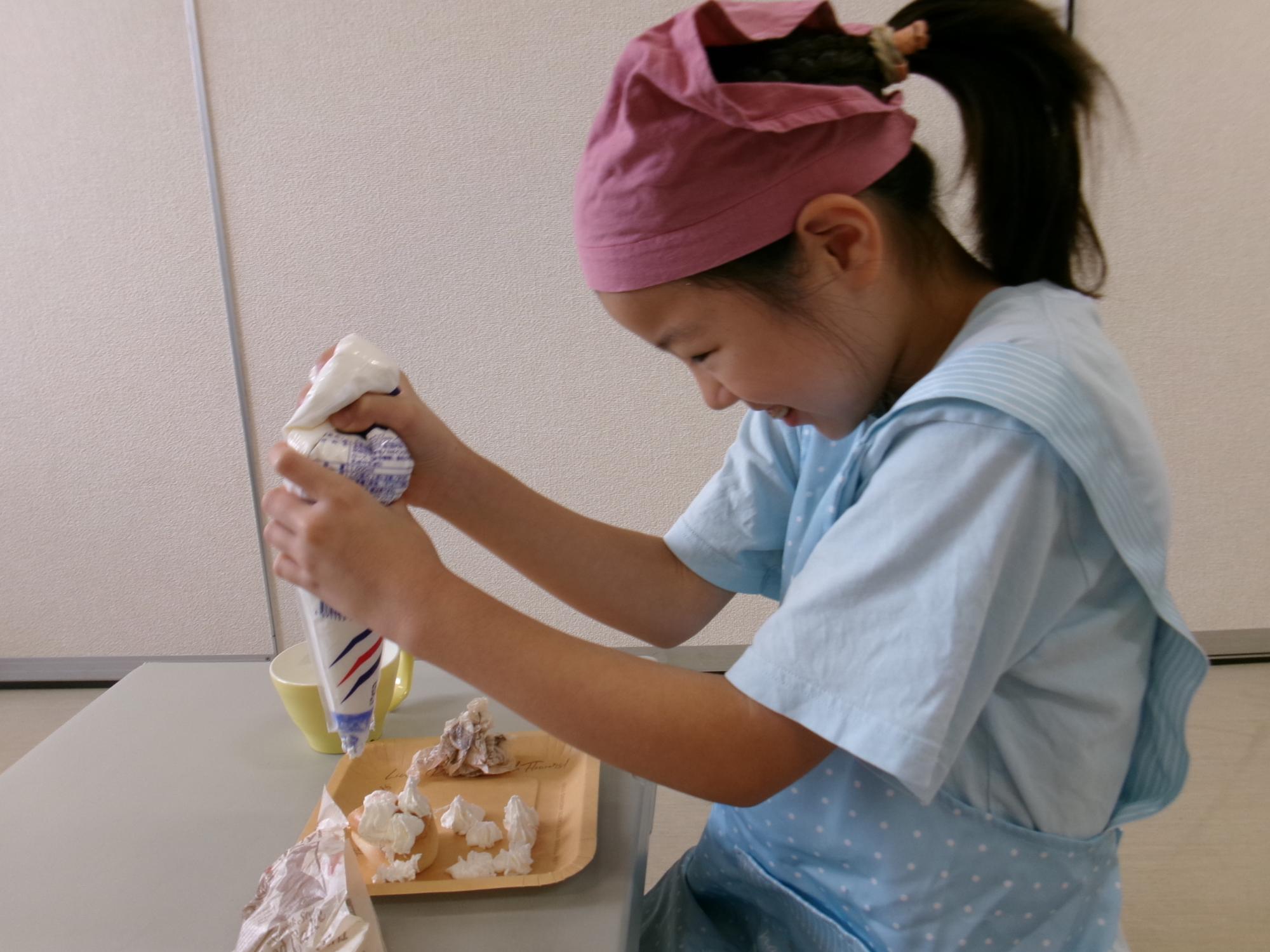 生クリームを絞る小学生児童の様子の写真