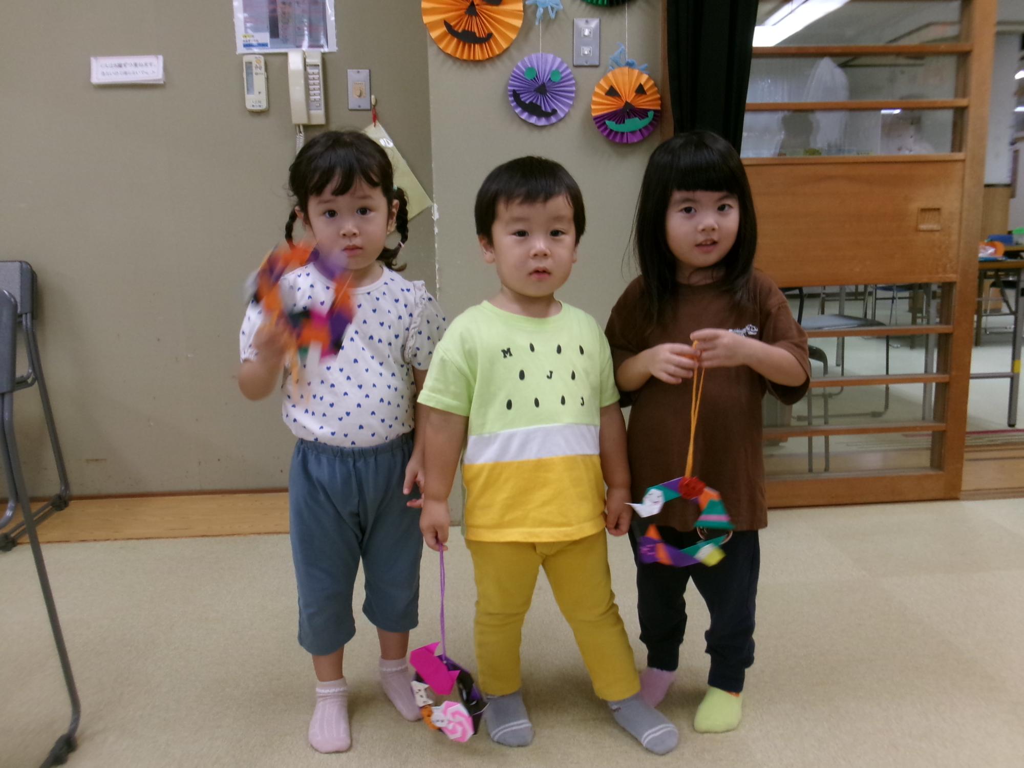 ハロウィンリースを持って写真を撮る乳幼児3人の写真