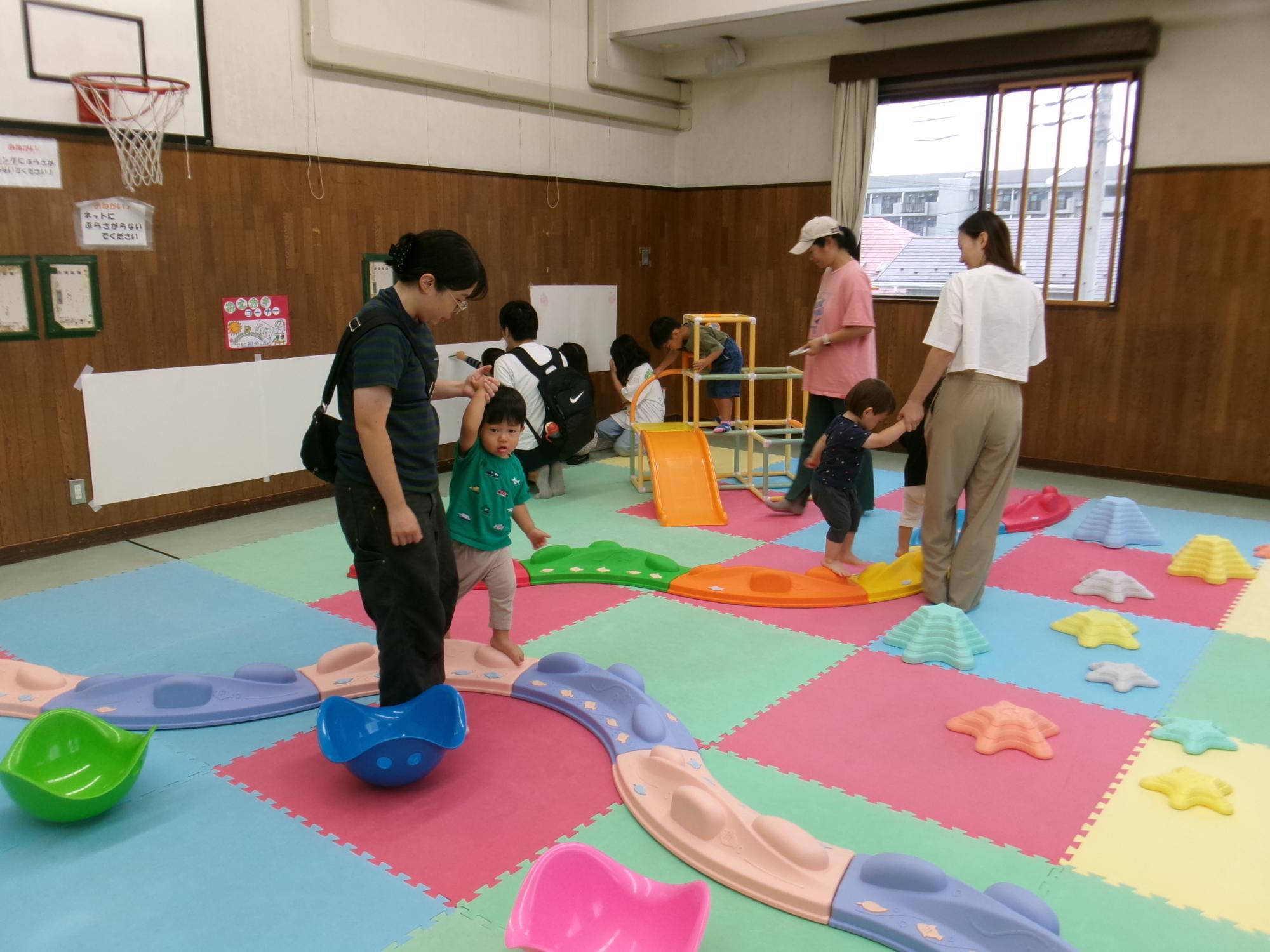 ちびっこパークの遊具で遊ぶ乳幼児親子の様子の写真