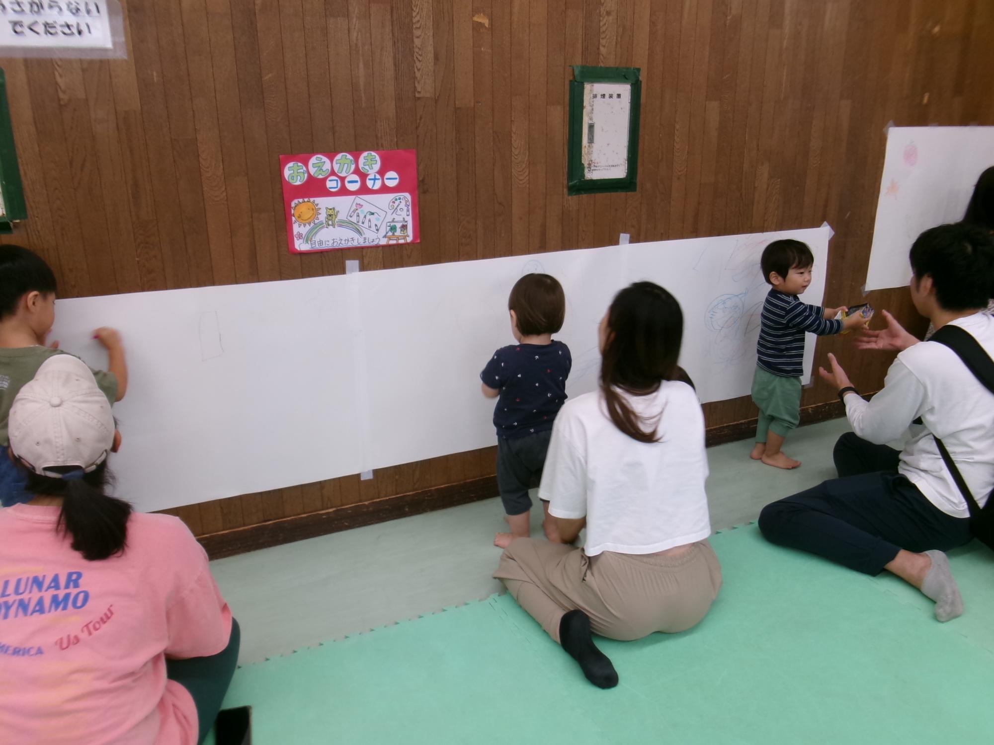 ちびっこパークのお絵描きコーナーで絵を描く幼児親子の様子の写真