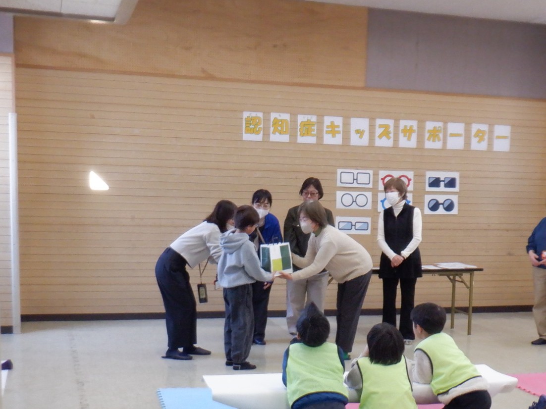 認知症サポーターの証「ロバ隊長」のグッズを贈呈されている様子の写真