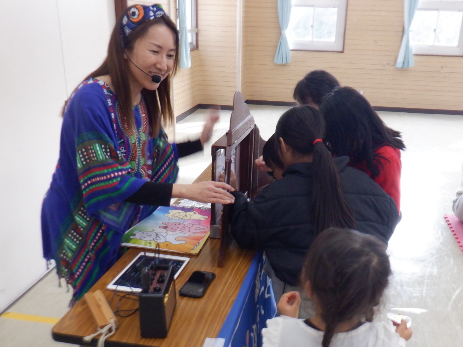 紙芝居にシールを貼って物語を完成させる幼児と小学生児童の写真