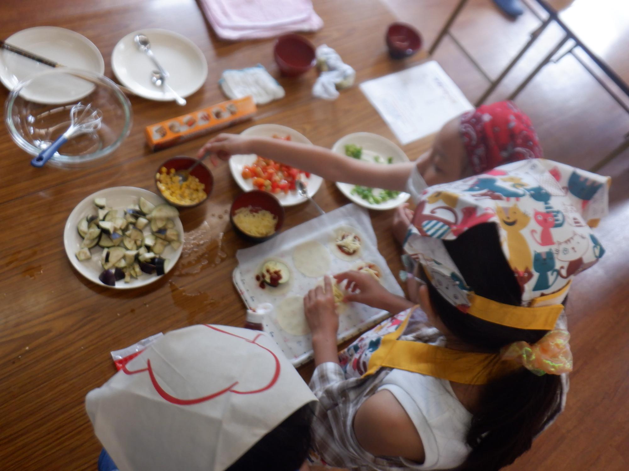 ピザにトッピングしている子どもたち