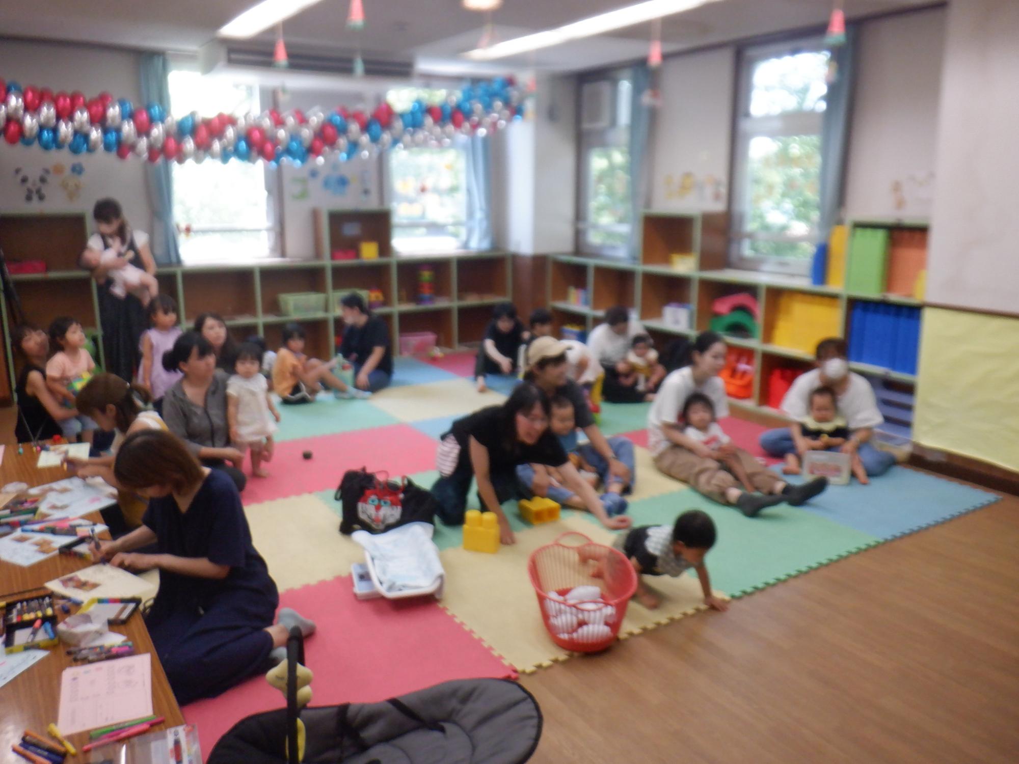 ゆうことぴっぴが紙芝居をしているのを聞いている乳幼児親子