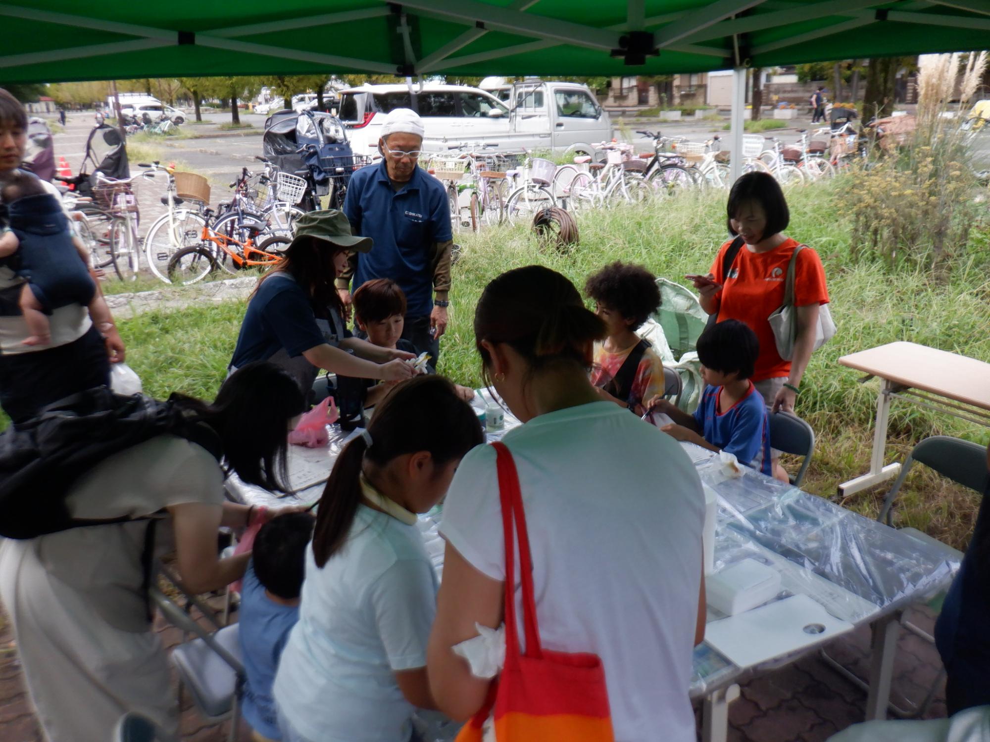 野外ブースにて葉っぱスタンプに挑戦している参加者の写真