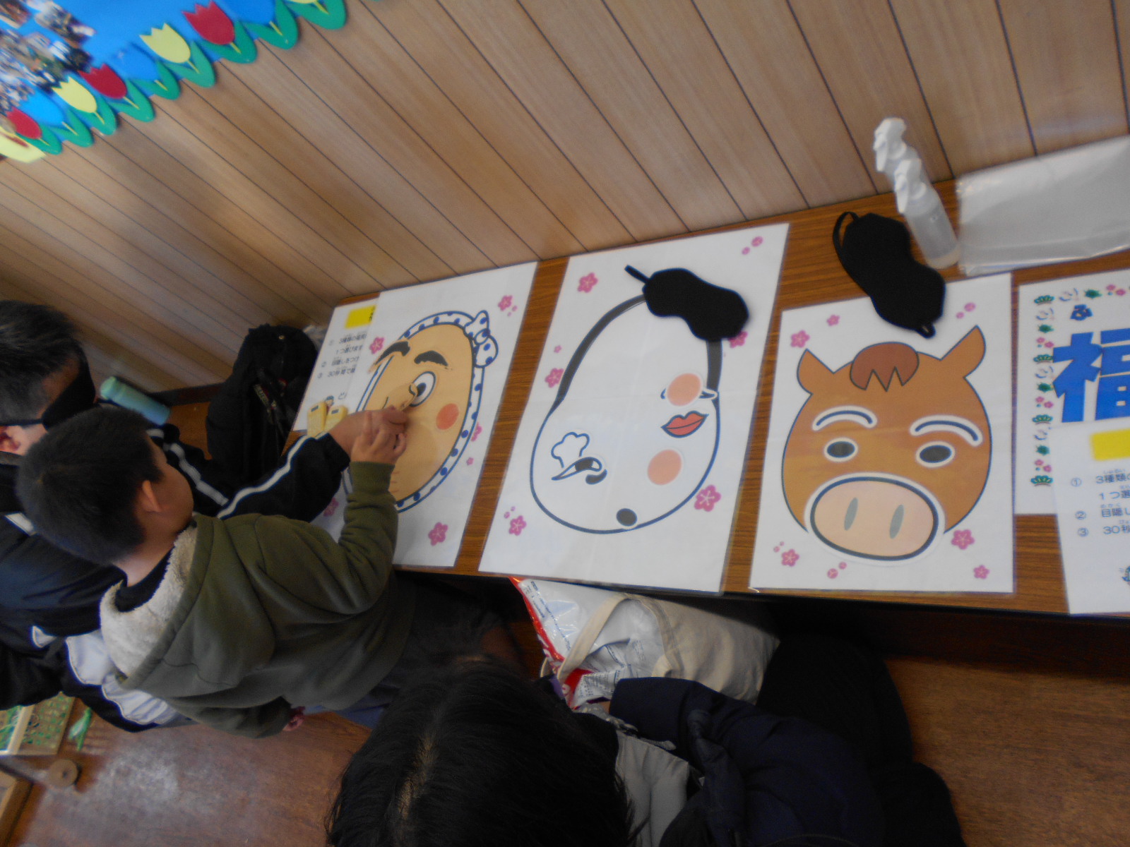 目隠しをして福笑いに挑戦している親子の写真