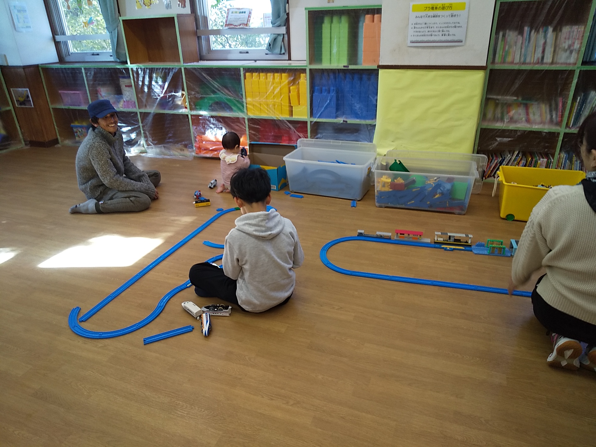 ひよこルームでプラ電車を楽しむ親子の写真