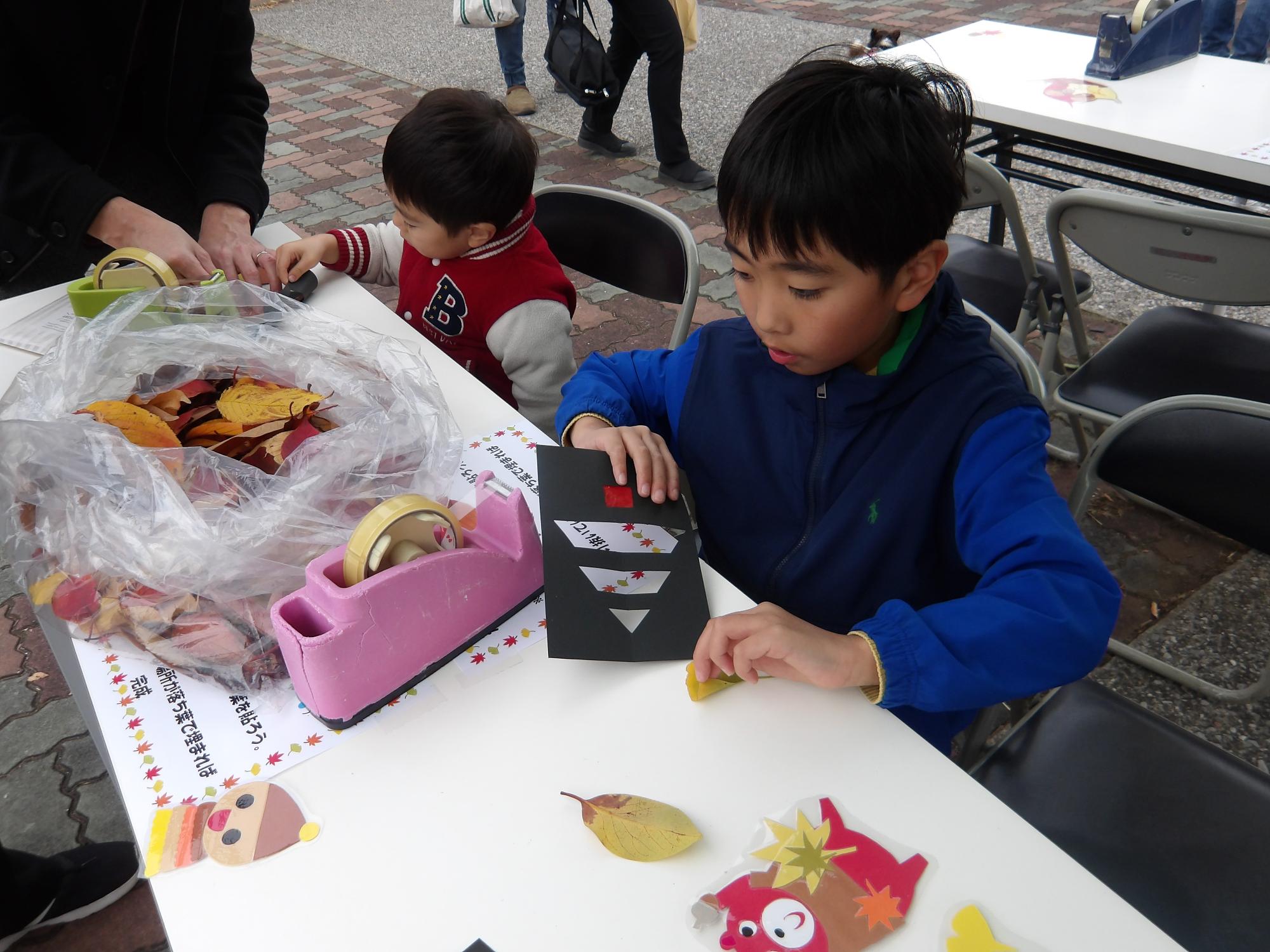 落ち葉でステンドグラフをしている子ども