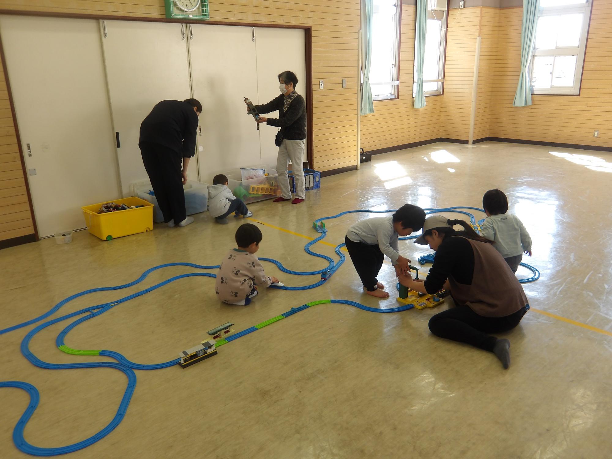プラ電車の線路をつくる幼児たちの様子