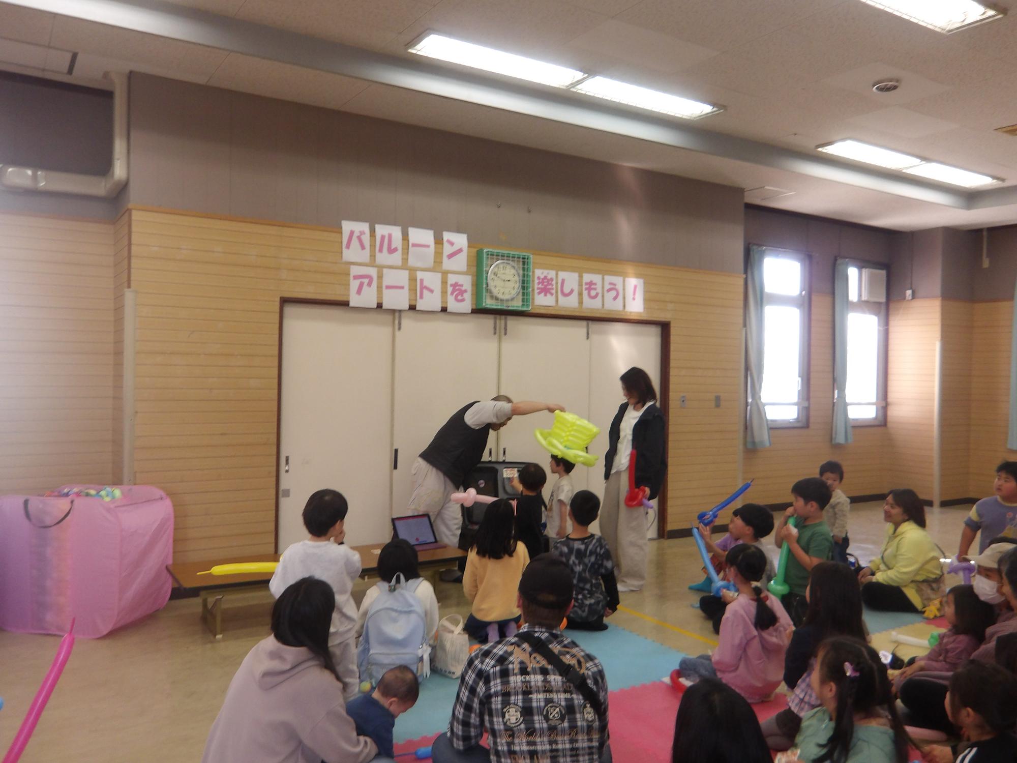 抽選であたったバルーン帽子をもらう小学生の写真