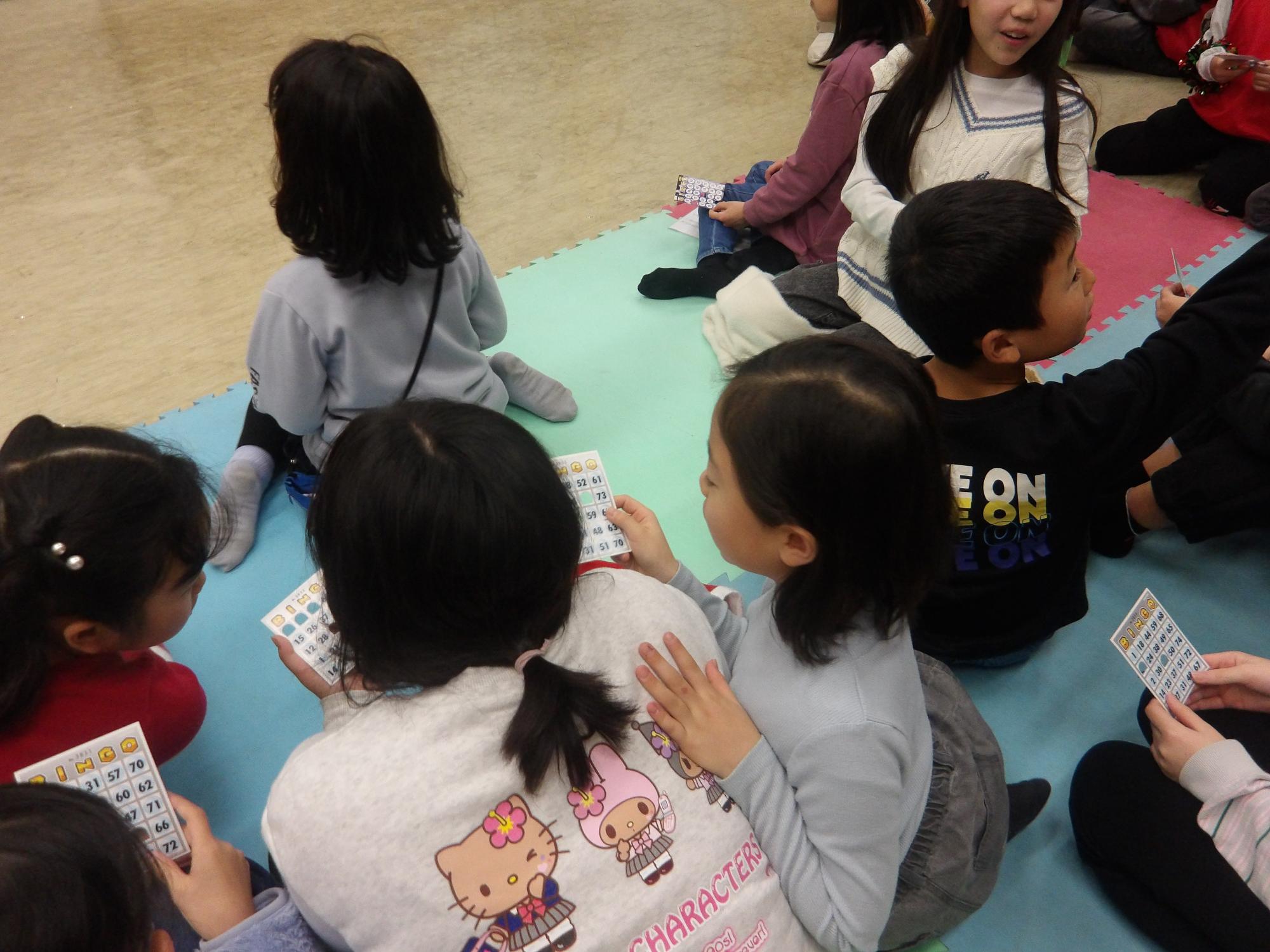 ビンゴ大会で、あいた数字を確認している子どもたちの様子