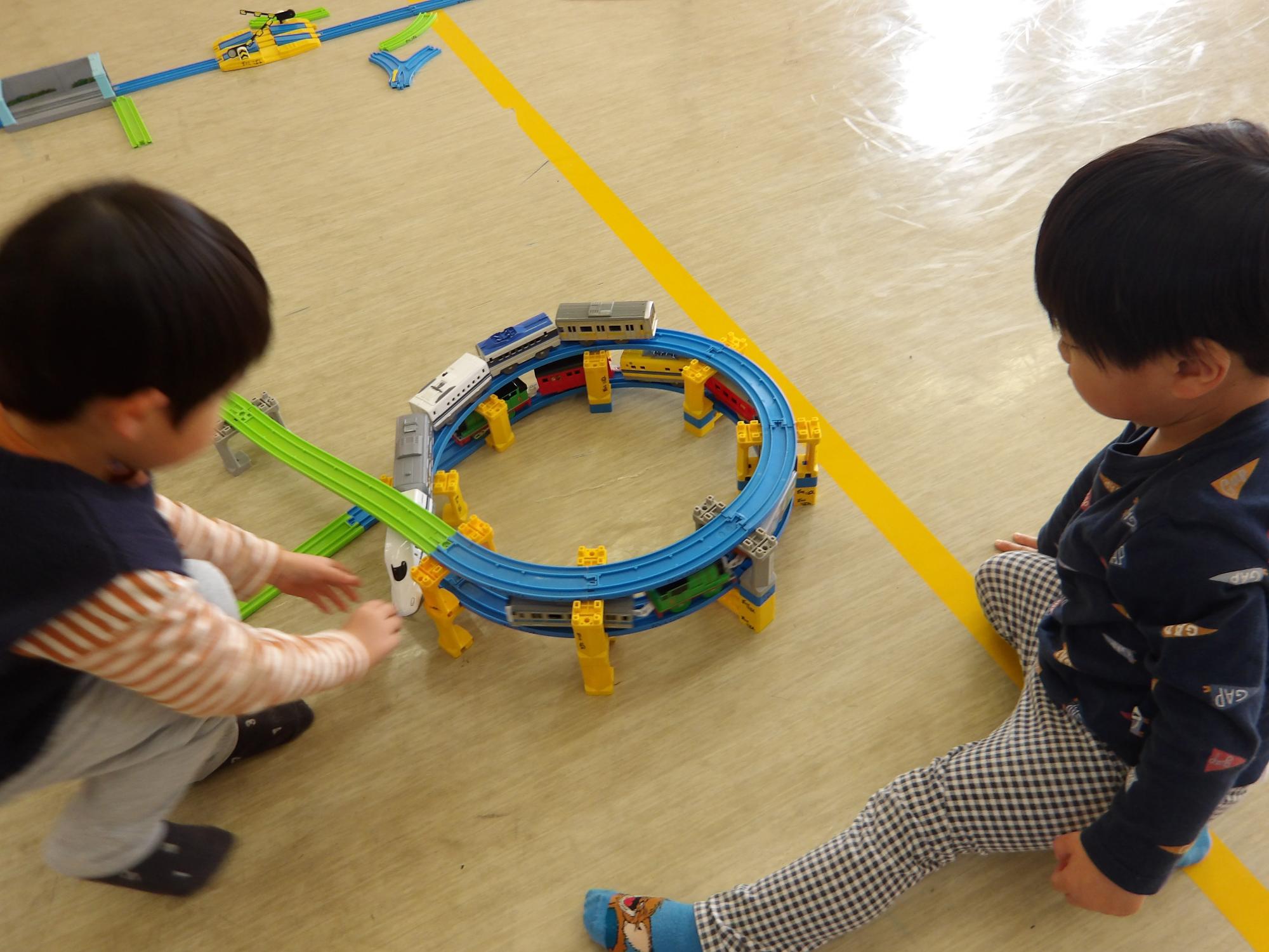 立体線路に電車を走らせて遊ぶ幼児の写真
