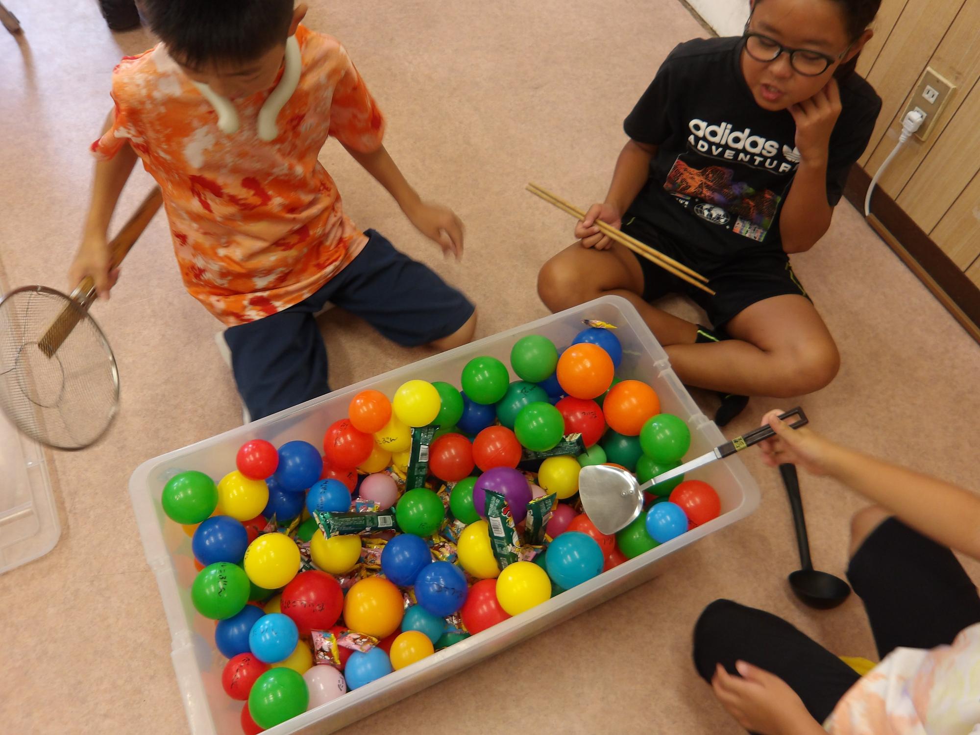 子どもブースで行う「おかしすくい」に向け、どのような道具を使うか実験している様子の写真